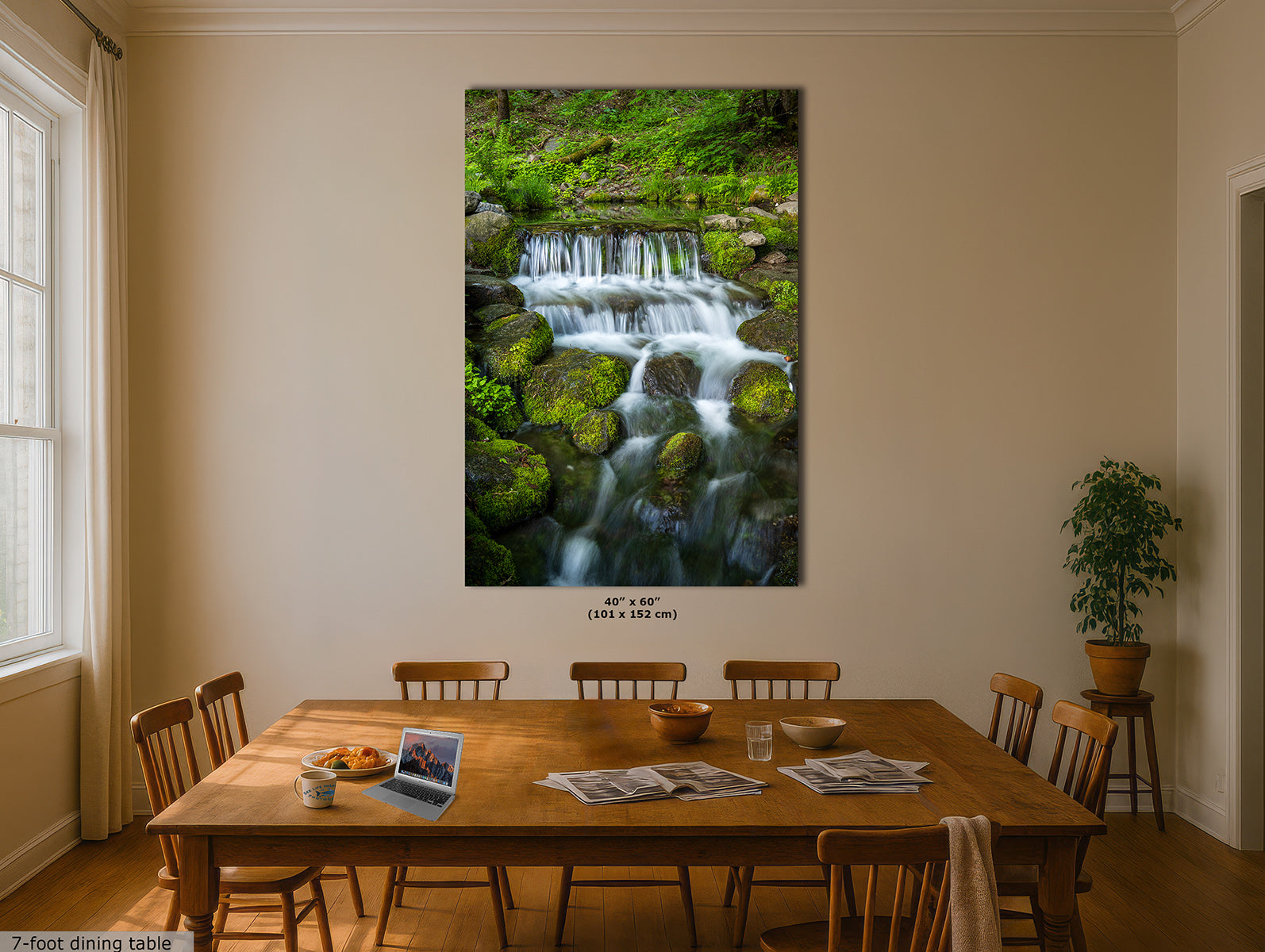 A large vertical wall art print showing a lush green forest waterfall, displayed on a beige dining room wall above a wooden dining table and chairs.