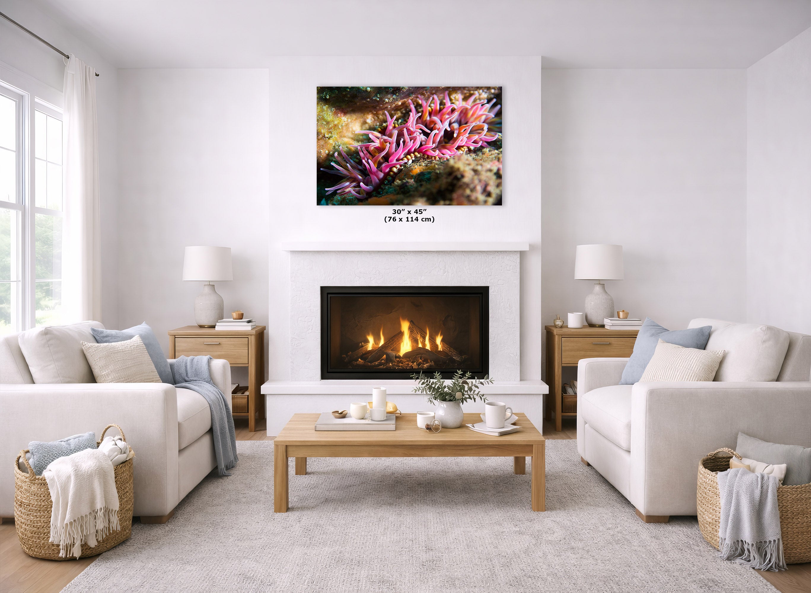 A wall art print of pink sea anemones is displayed above a white fireplace in a bright, modern living room with two white sofas, a wooden coffee table, and a light gray rug.