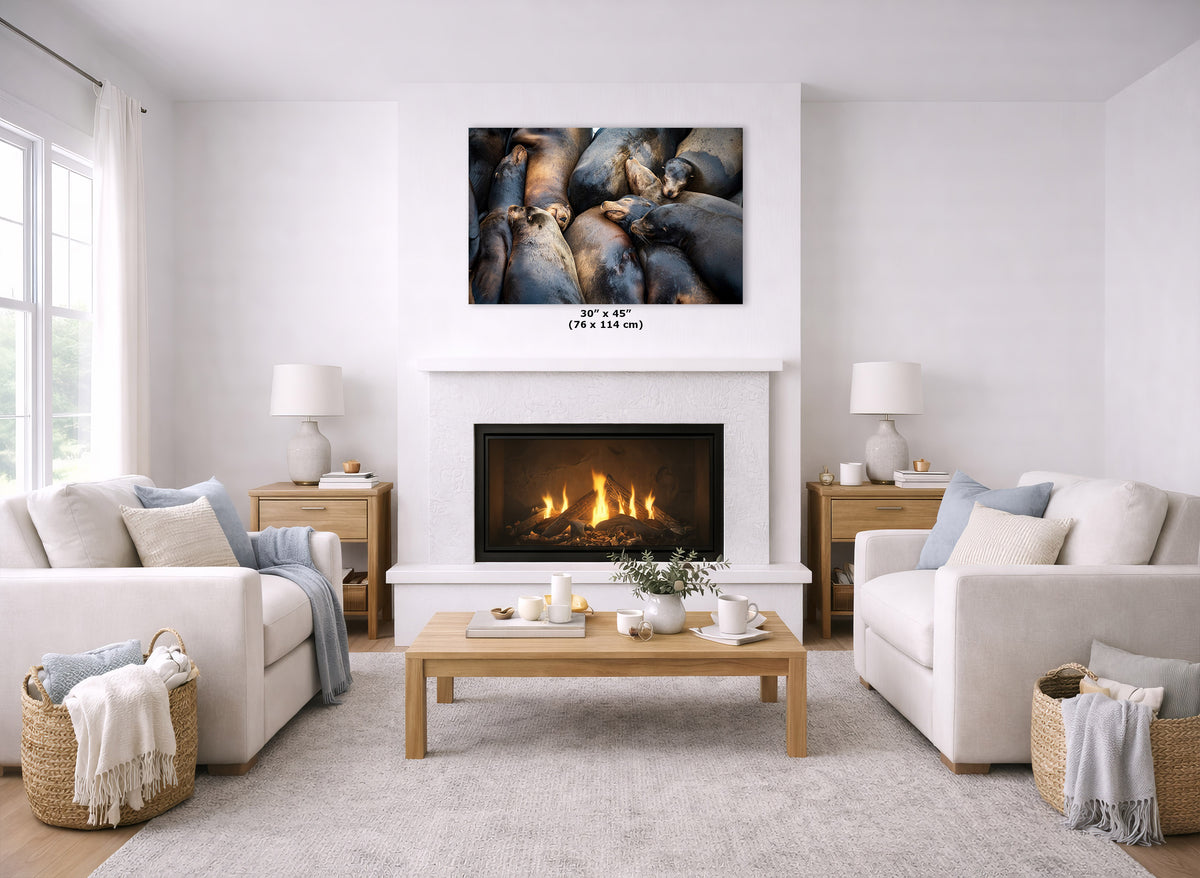 A wall art print displayed above a white fireplace in a bright, modern living room with two cream sofas, a wooden coffee table, and a light rug.