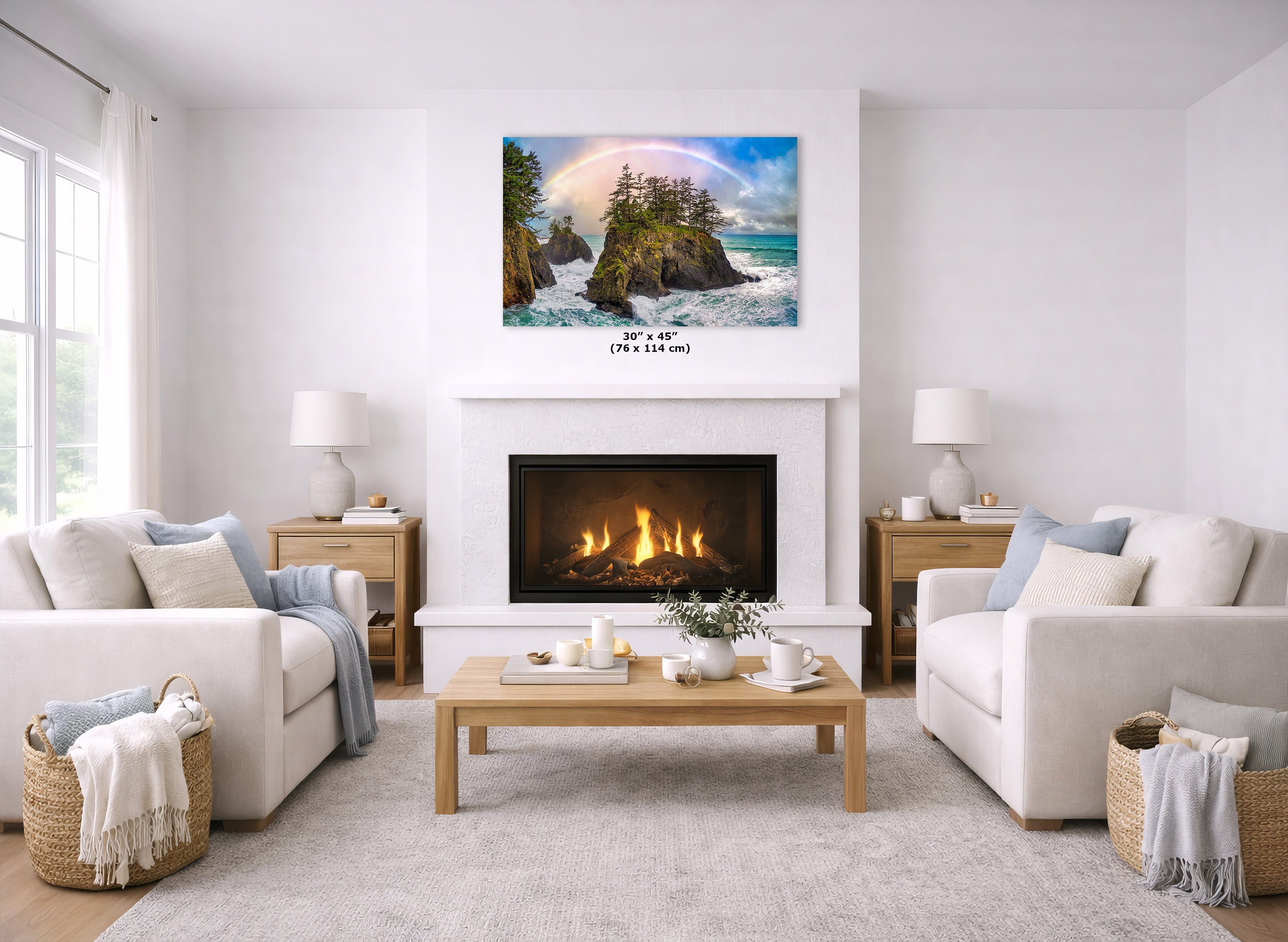 A square canvas wall art print depicting a coastal landscape with a rainbow over rocky cliffs and ocean waves, displayed above a fireplace in a bright, modern living room with white sofas and a wooden coffee table.