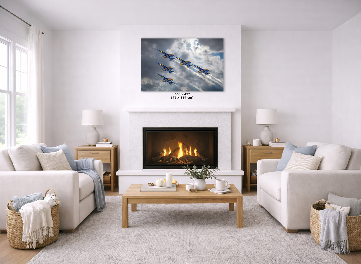 A wall art print showing a formation of blue fighter jets flying through dramatic clouds, displayed above a white fireplace in a bright, modern living room with two cream sofas and a wooden coffee table.