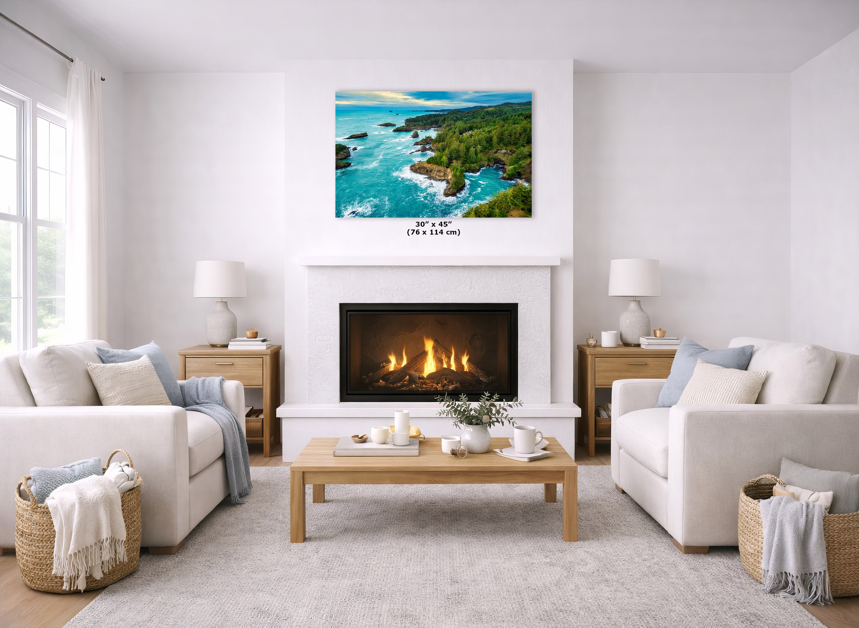 A coastal landscape print hangs above a white fireplace in a bright, modern living room with two cream sofas, a wooden coffee table, and woven baskets.