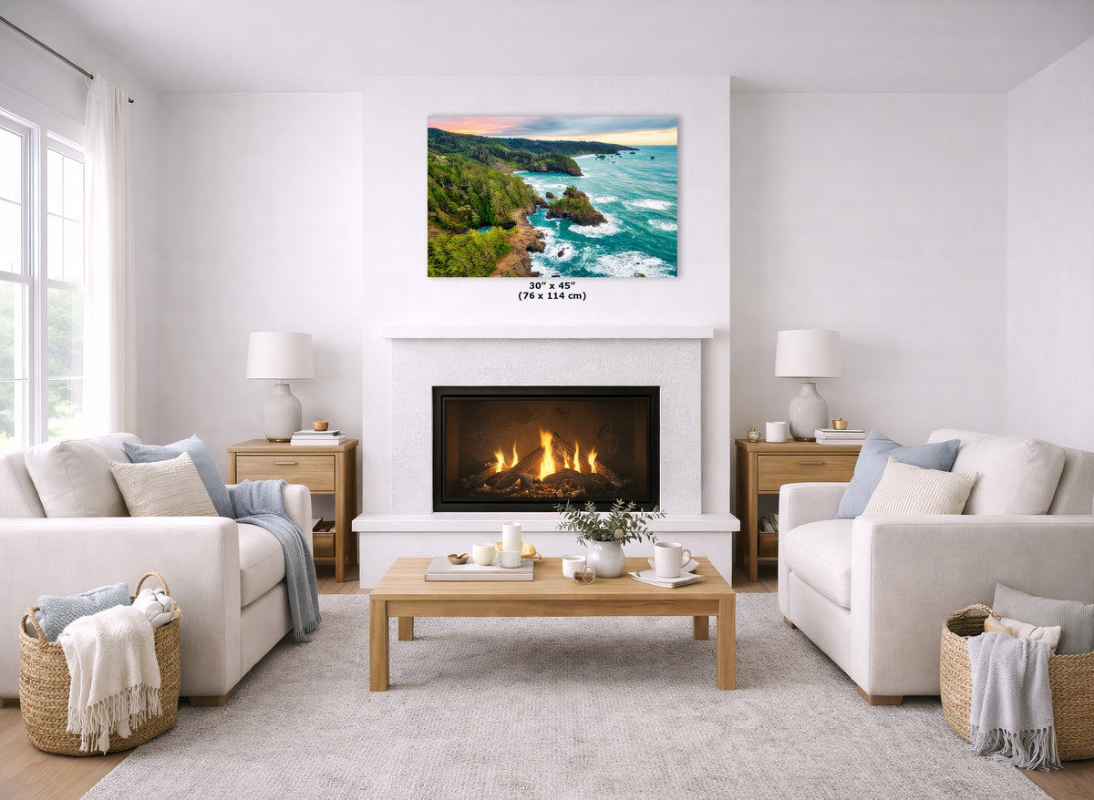 A coastal landscape print hangs above a white fireplace in a bright, modern living room with two cream sofas, a wooden coffee table, and woven baskets.