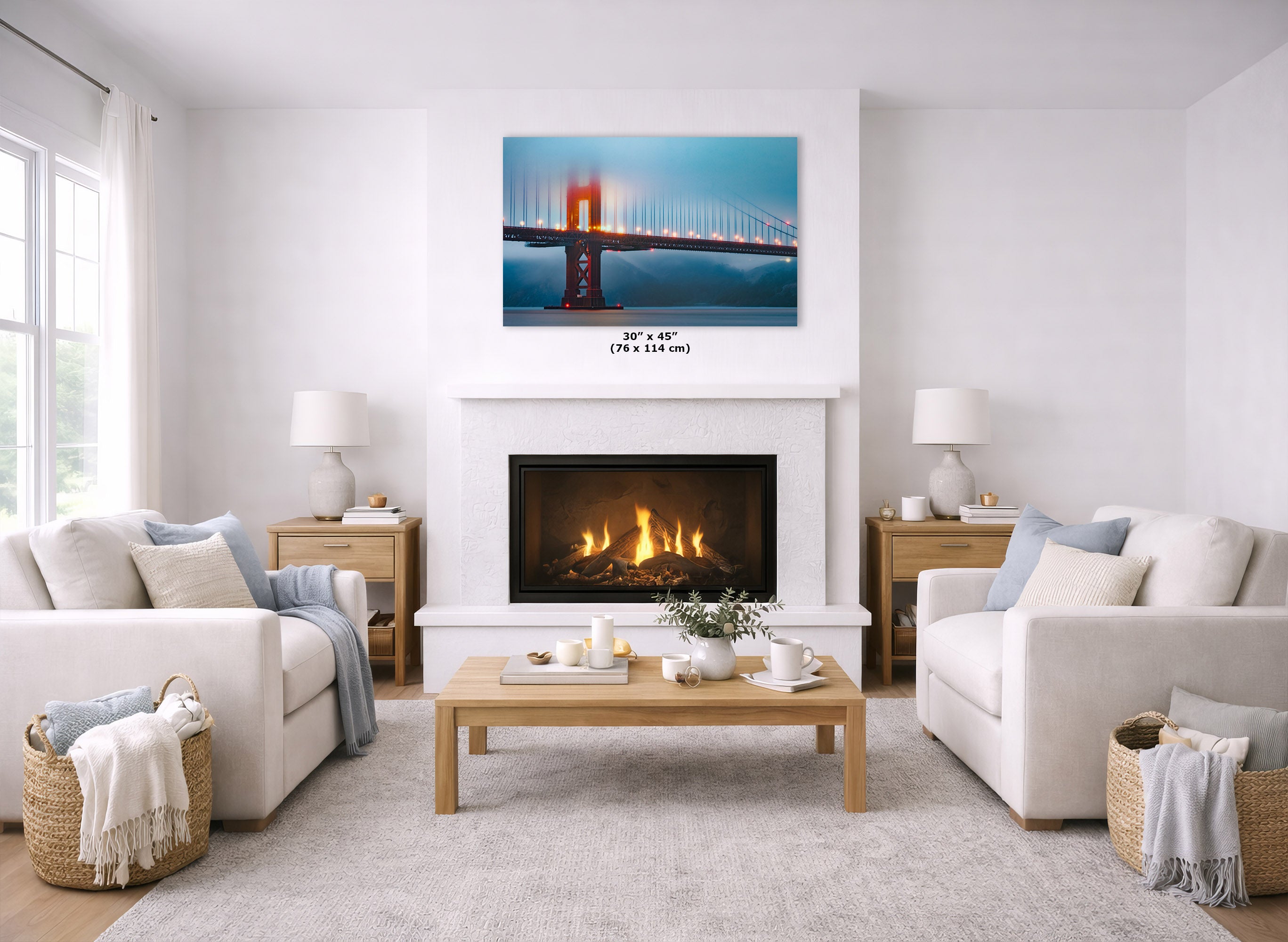 A wall art print of the Golden Gate Bridge hangs above a fireplace in a bright, modern living room with two white sofas, a wooden coffee table, and a light rug. The print is shown with dimensions labeled below it.