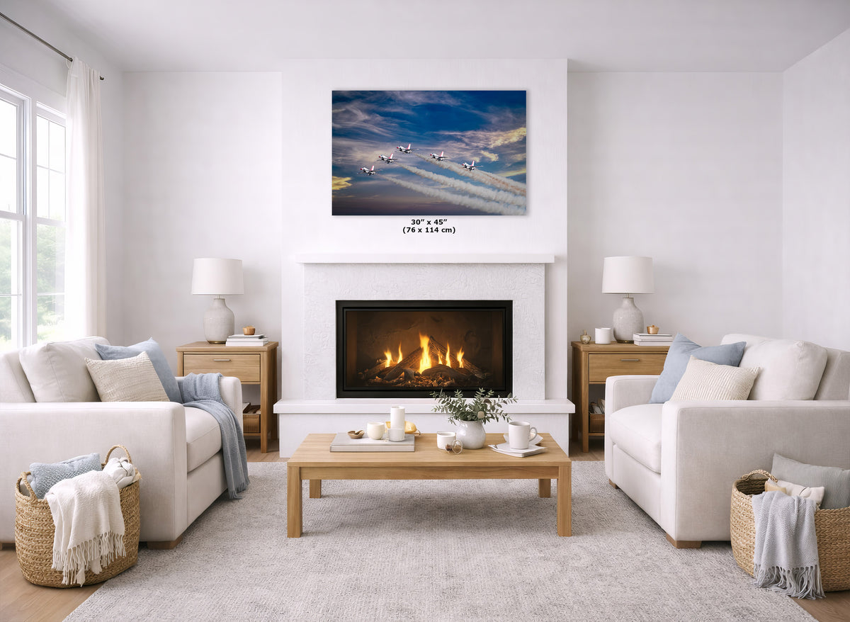 A wall art print depicting a dramatic blue sky with flying airplanes over a snowy mountain range, displayed above a white fireplace in a bright, modern living room with two white sofas and a wooden coffee table.