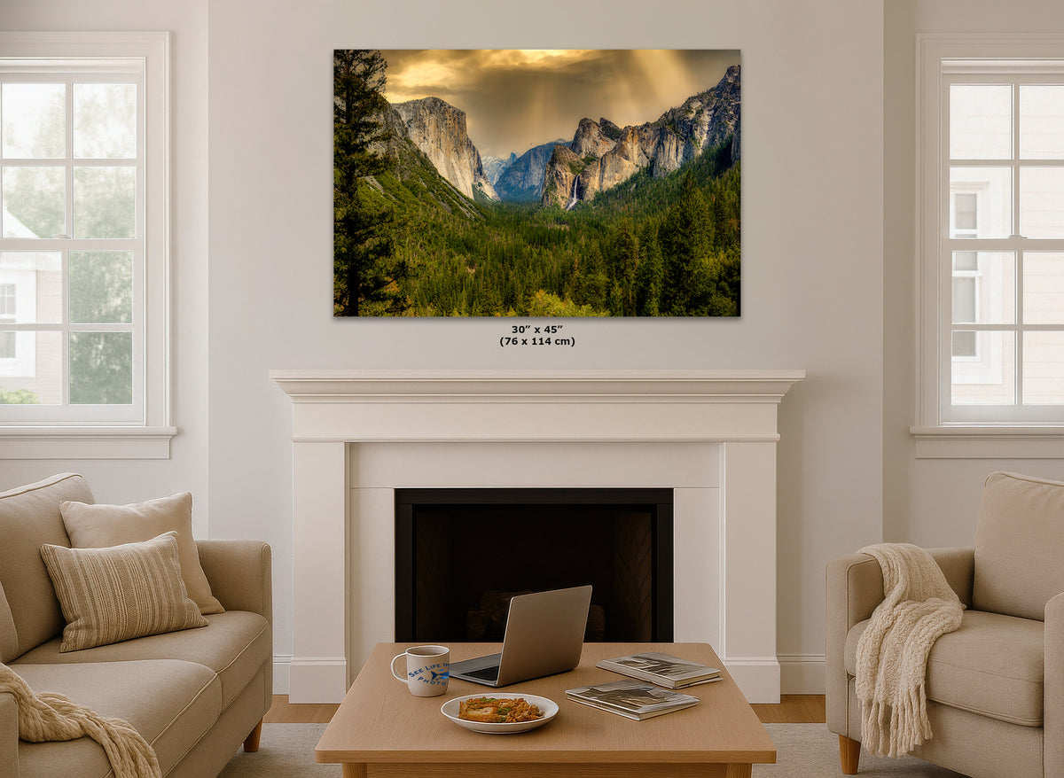 A framed wall art print showing a dramatic mountain valley landscape with green trees and a cloudy sky, displayed above a white fireplace mantel in a bright living room. Small text below the print reads 30 x 45 in (76 x 144 cm).