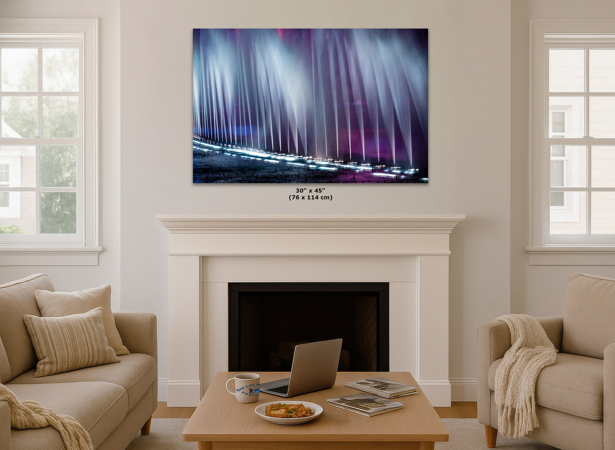 A wall art print showing an abstract purple and blue light effect, displayed above a white fireplace mantel in a modern living room setting with beige sofas and a wooden coffee table.