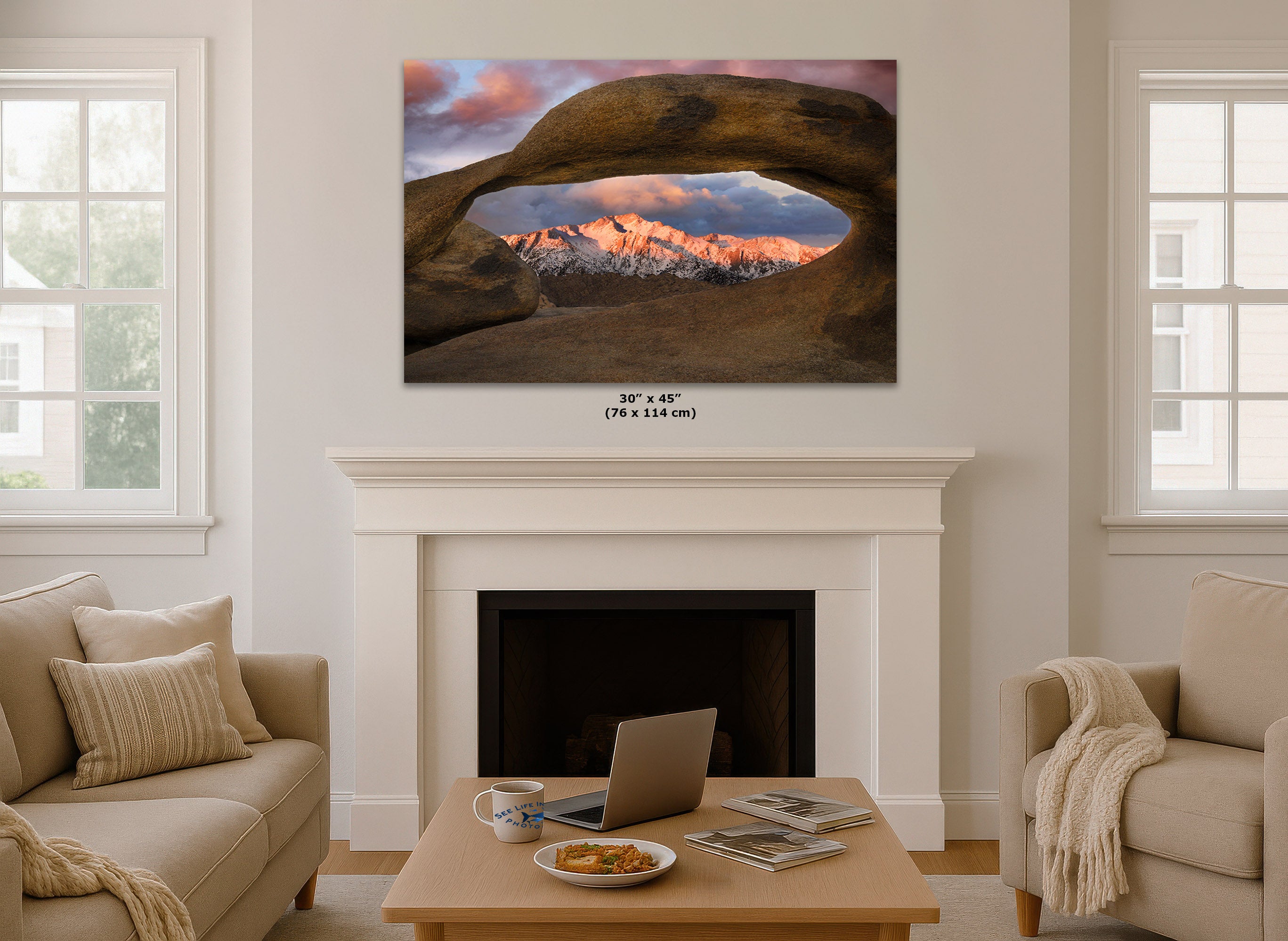 Living room with a large wall art print hanging over the fireplace that shows a picture of the snow-capped mountains of Lone Pine as seen through Mobius Arch at the Alabama Hills.