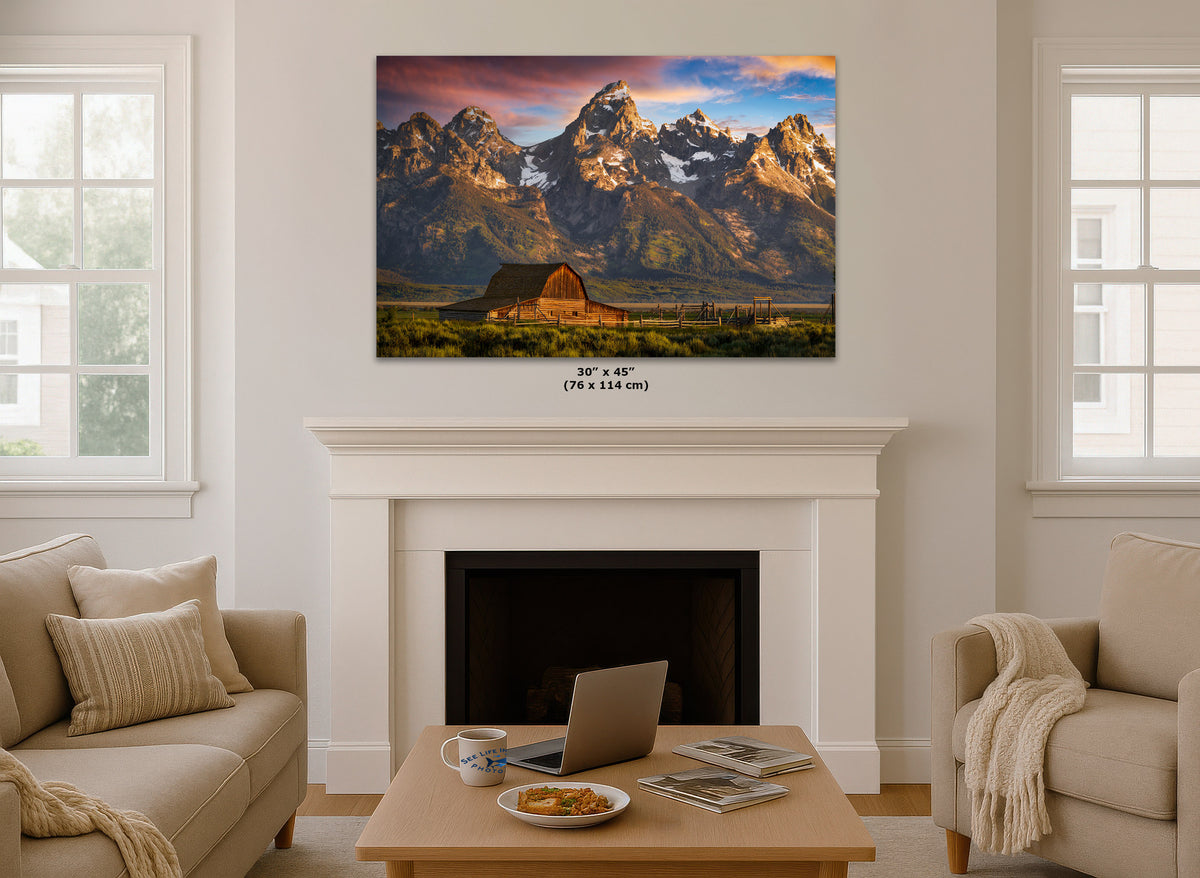 A wall art print showing a mountain landscape with a barn is displayed above a white fireplace in a styled living room. The print includes size text below it reading 30 x 45 in (76 x 114 cm).