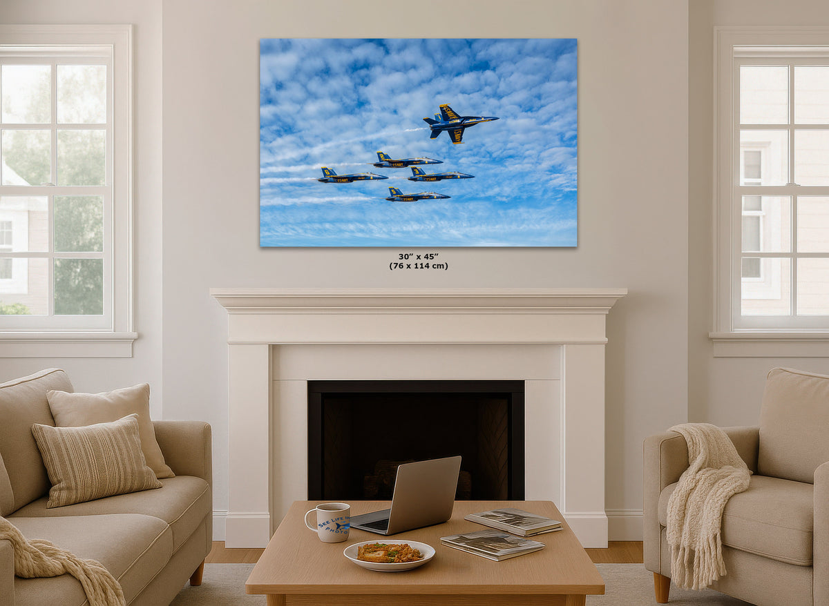 A large wall art print showing a formation of fighter jets flying through a blue sky with white clouds, displayed above a white fireplace mantel in a bright living room. The print includes size text below it reading 30" x 45" (76 x 114 cm).