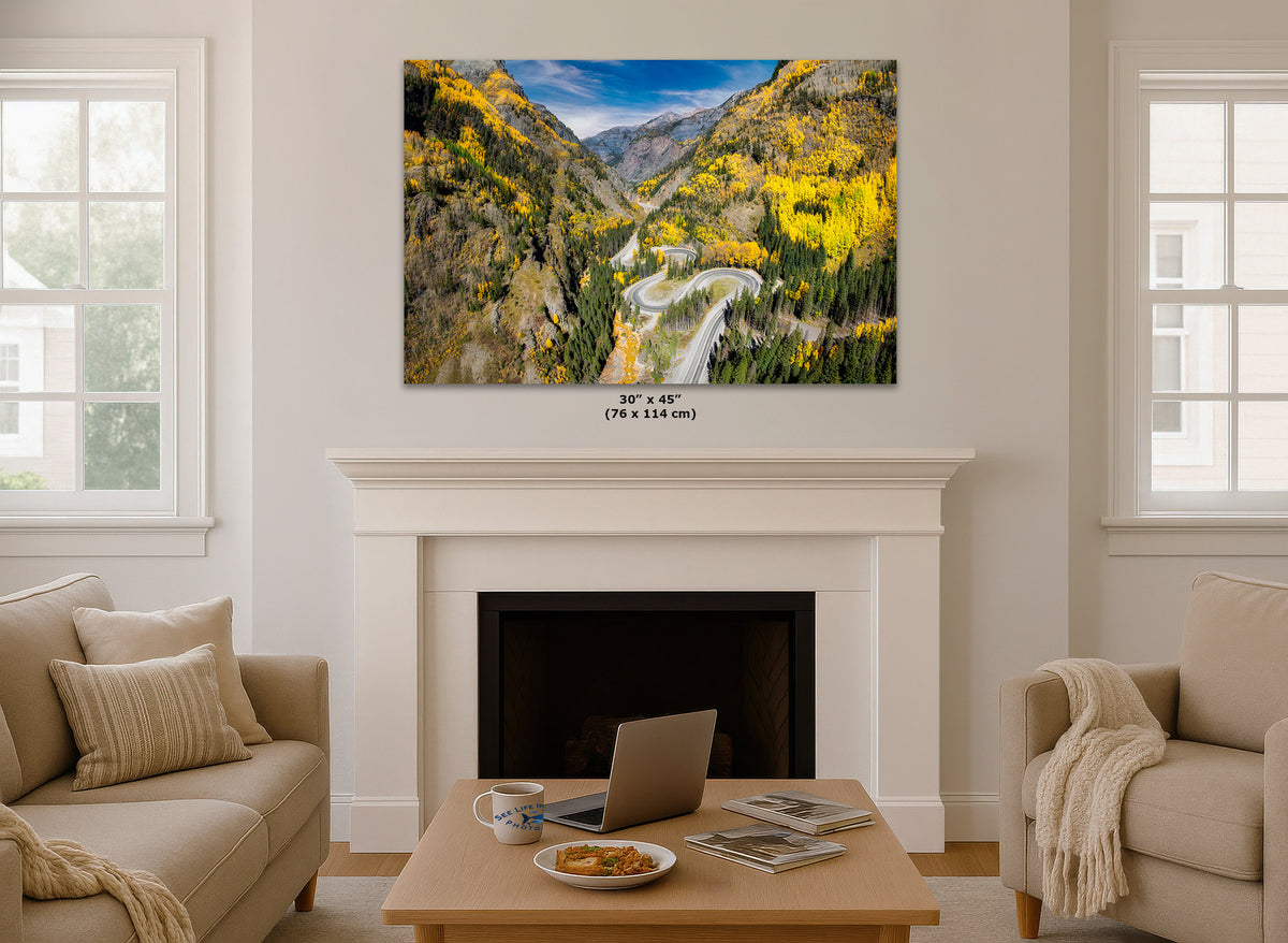 Living room with a large wall art print displaying a scenic Colorado mountain landscape of Million Dollar Highway with aspen trees hanging above a fireplace.