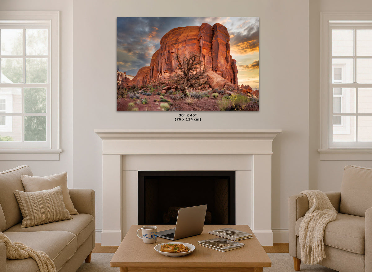 A wall art print depicting a desert rock formation at sunset, displayed above a white fireplace mantel in a bright living room. The print includes size text below it reading 30 x 45 in (76 x 114 cm).