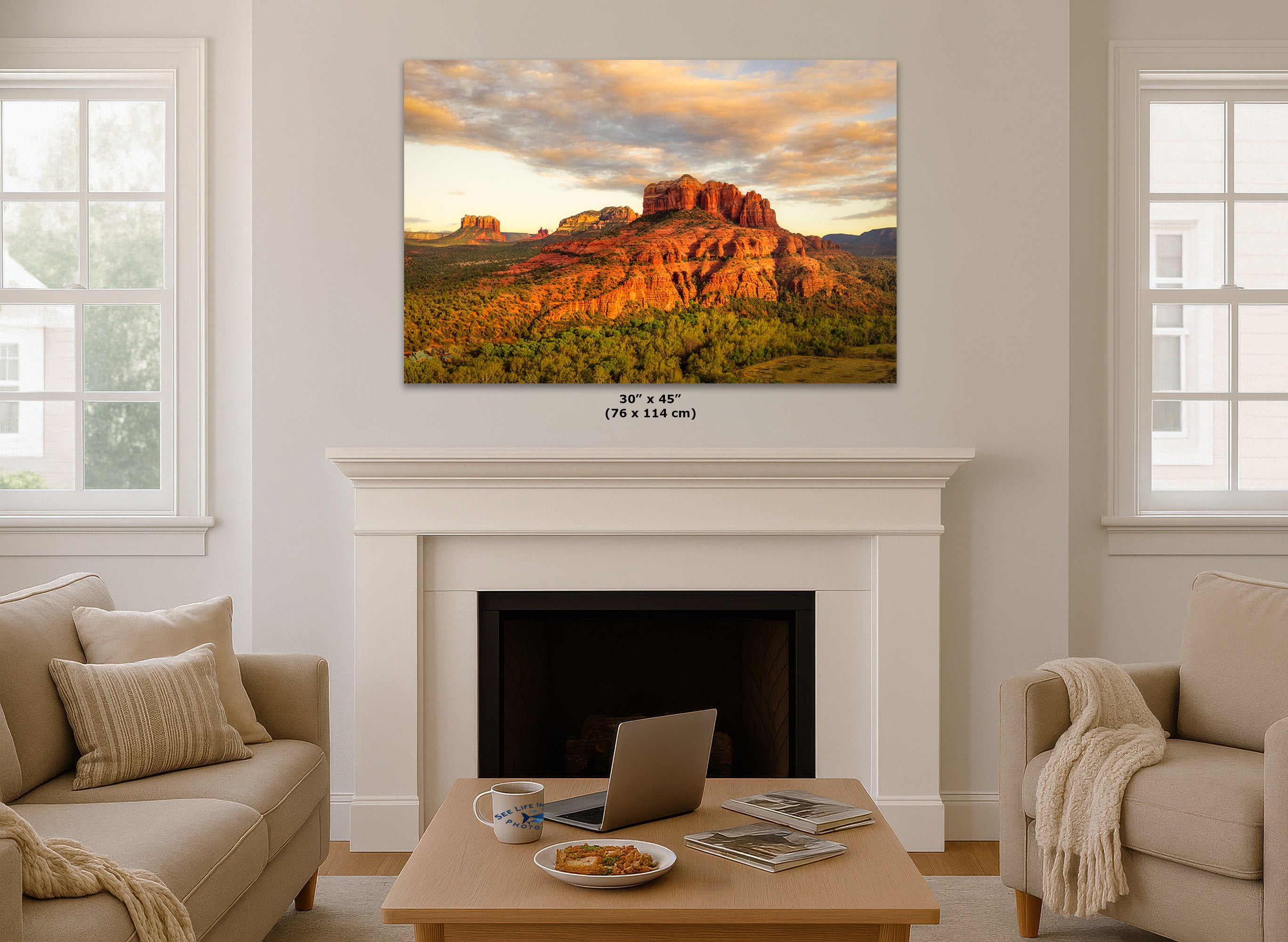 Living room with a large wall art of a sunset over red rock formations above a fireplace.