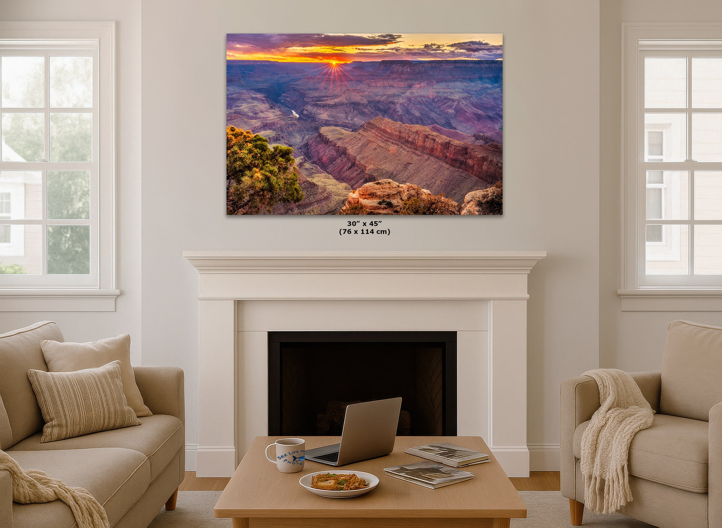 A 30x45 inch canvas print of a Grand Canyon sunset is displayed on a white fireplace mantel in a modern living room setting with beige sofas and a wooden coffee table.