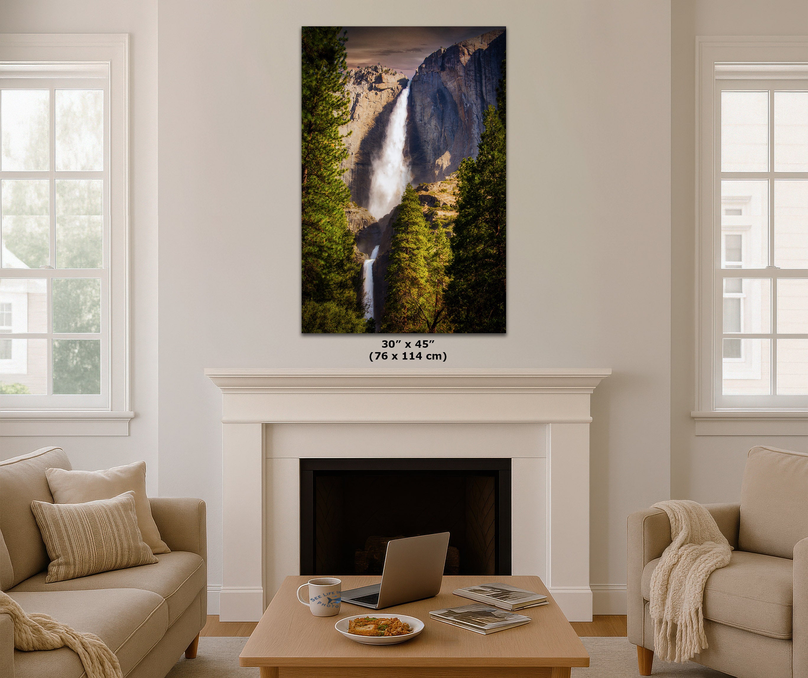 A vertical canvas print of Yosemite Falls, 30" x 45" (76 x 114 cm), displayed on a white wall above a fireplace in a modern, neutral-toned living room setting.