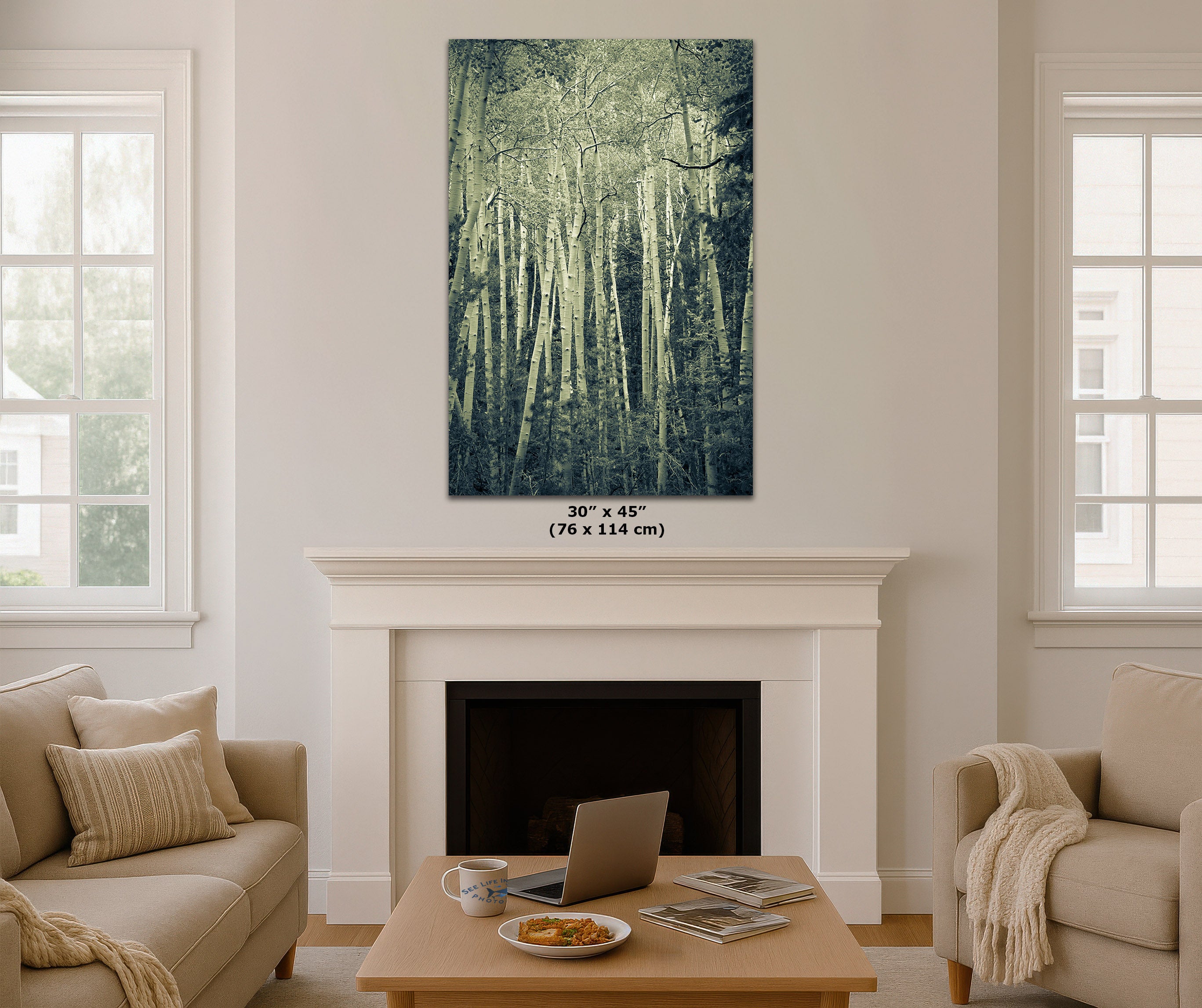 A vertical canvas wall art print depicting a misty green forest, displayed in a mockup living room above a white fireplace mantel. The image includes a size label '30" x 45" (76 x 114 cm)' printed directly on the canvas.