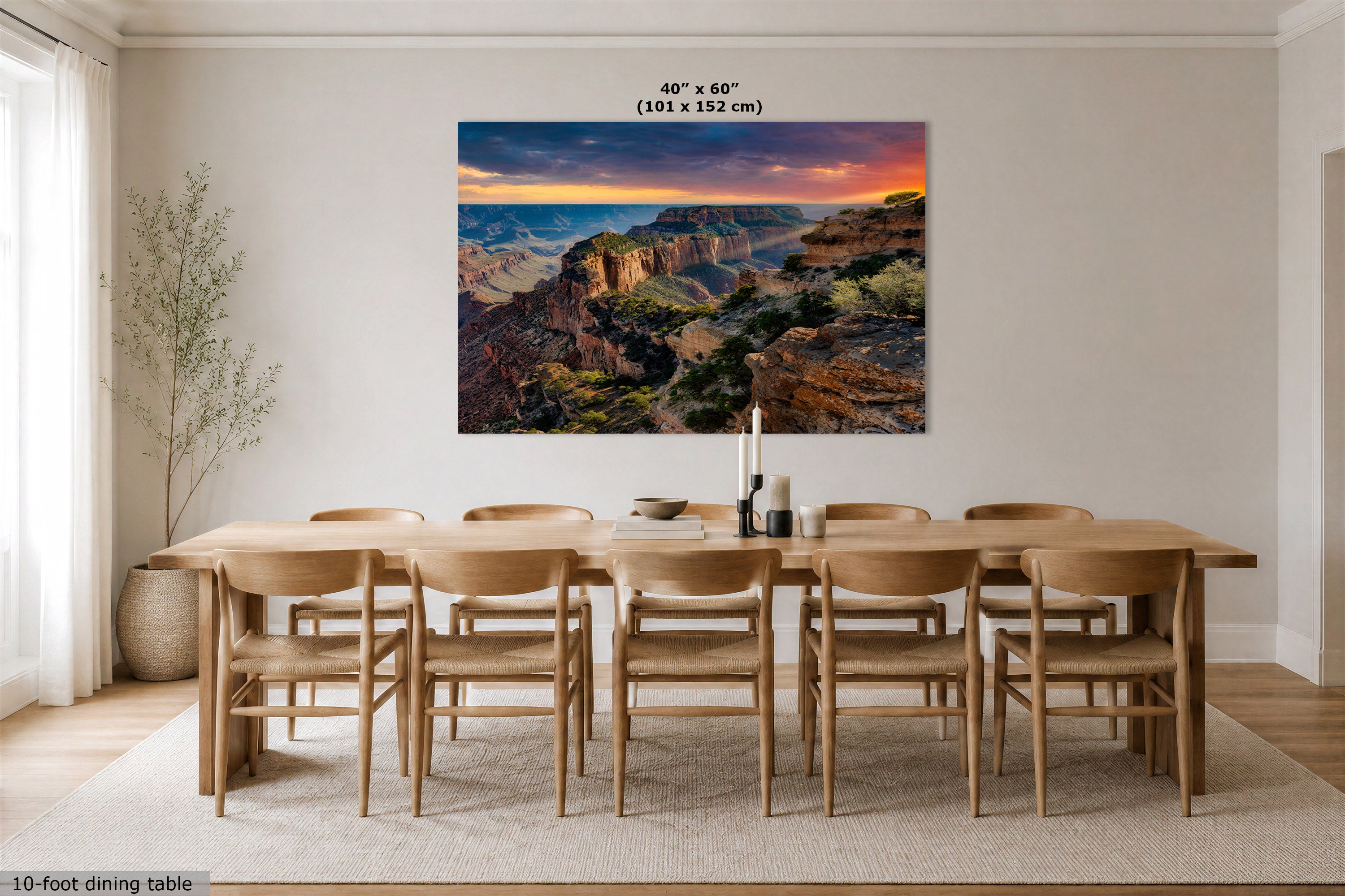 A large rectangular wall art print showing a canyon landscape at sunset hangs above a wooden dining table and chairs in a bright, modern dining room. The print includes the text '40" x 60" (101 x 152 cm)' at the top.