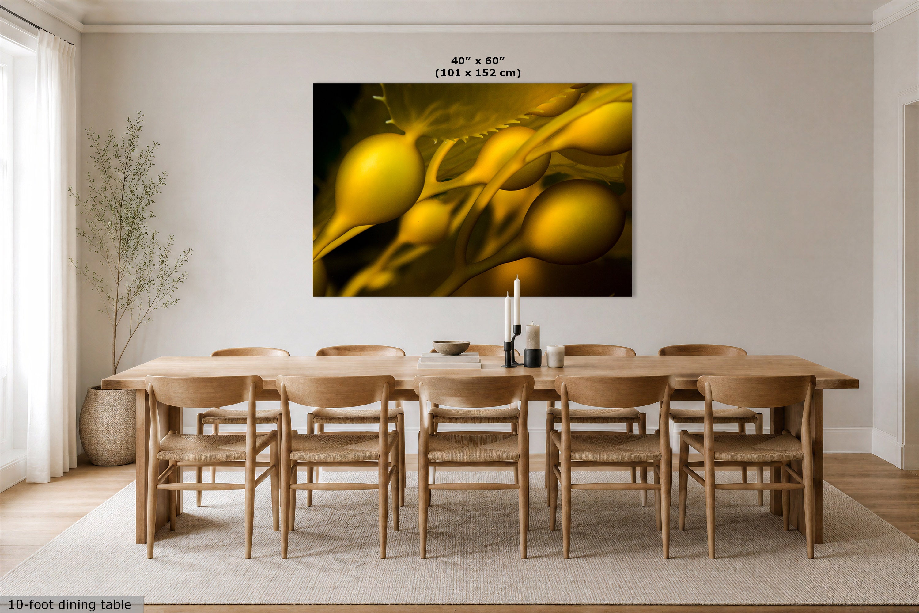A large rectangular wall art print showing an abstract underwater photograph, golden yellow forms on a black background, displayed above a wooden dining table and chairs in a bright, neutral dining room. Text at the top reads 40" x 60" (101 x 152 cm).