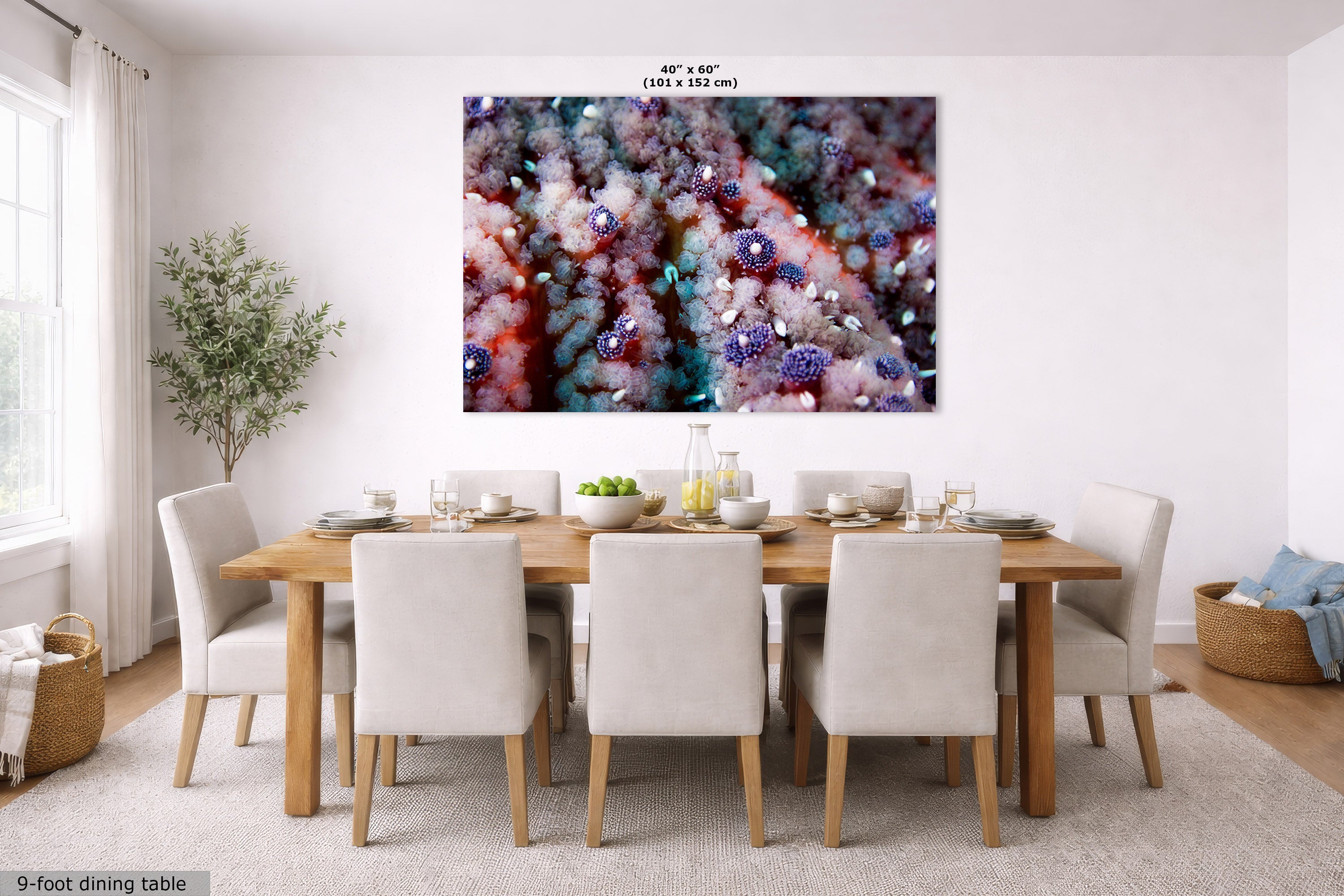 A large abstract wall art print with pink, purple, and white textures hangs above a wooden dining table with white upholstered chairs in a bright, modern dining room. Small text at the top of the artwork reads 40 x 60 inches, and text at the bottom left says 9-foot dining table.
