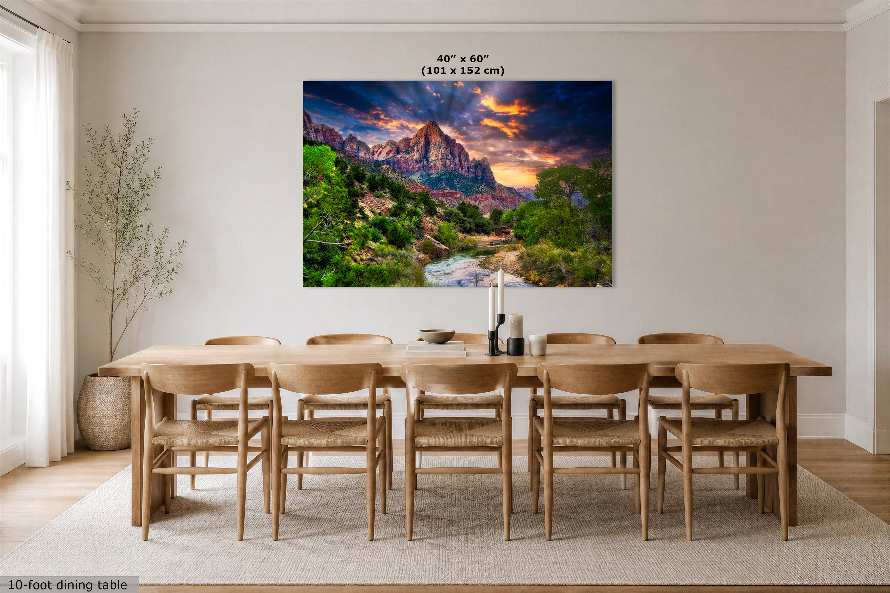 A large rectangular wall art print showing a colorful Watchman mountain landscape at sunset hangs above a wooden dining table and chairs in a bright dining room. The print includes text at the top reading 40 in x 60 in (101 x 152 cm).