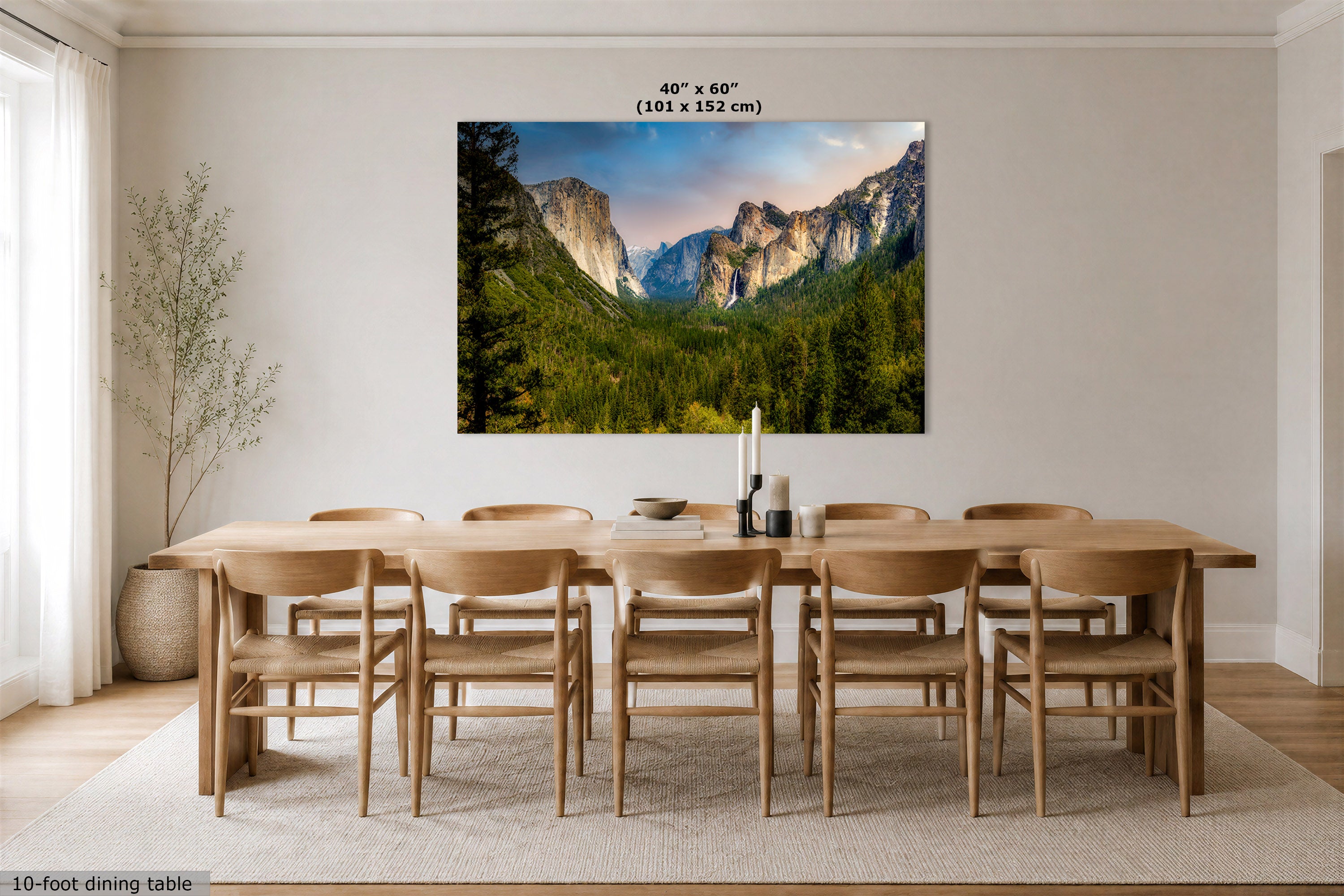 A large rectangular wall art print showing a mountain valley landscape hangs above a wooden dining table and chairs in a bright dining room. The print includes overlaid text reading 40" x 60" (101 x 152 cm).