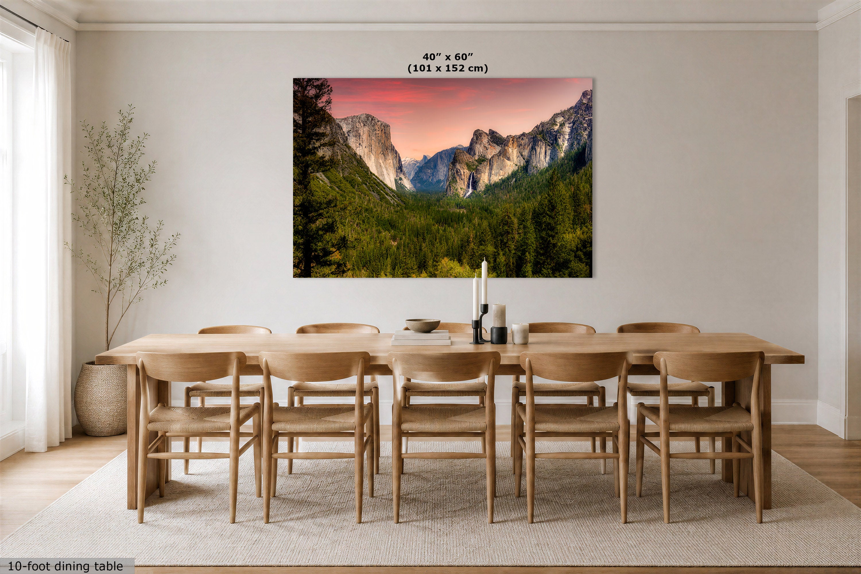 A 40" x 60" canvas print of a mountain valley landscape at sunset, displayed on a wall above a wooden dining table and chairs in a modern dining room.