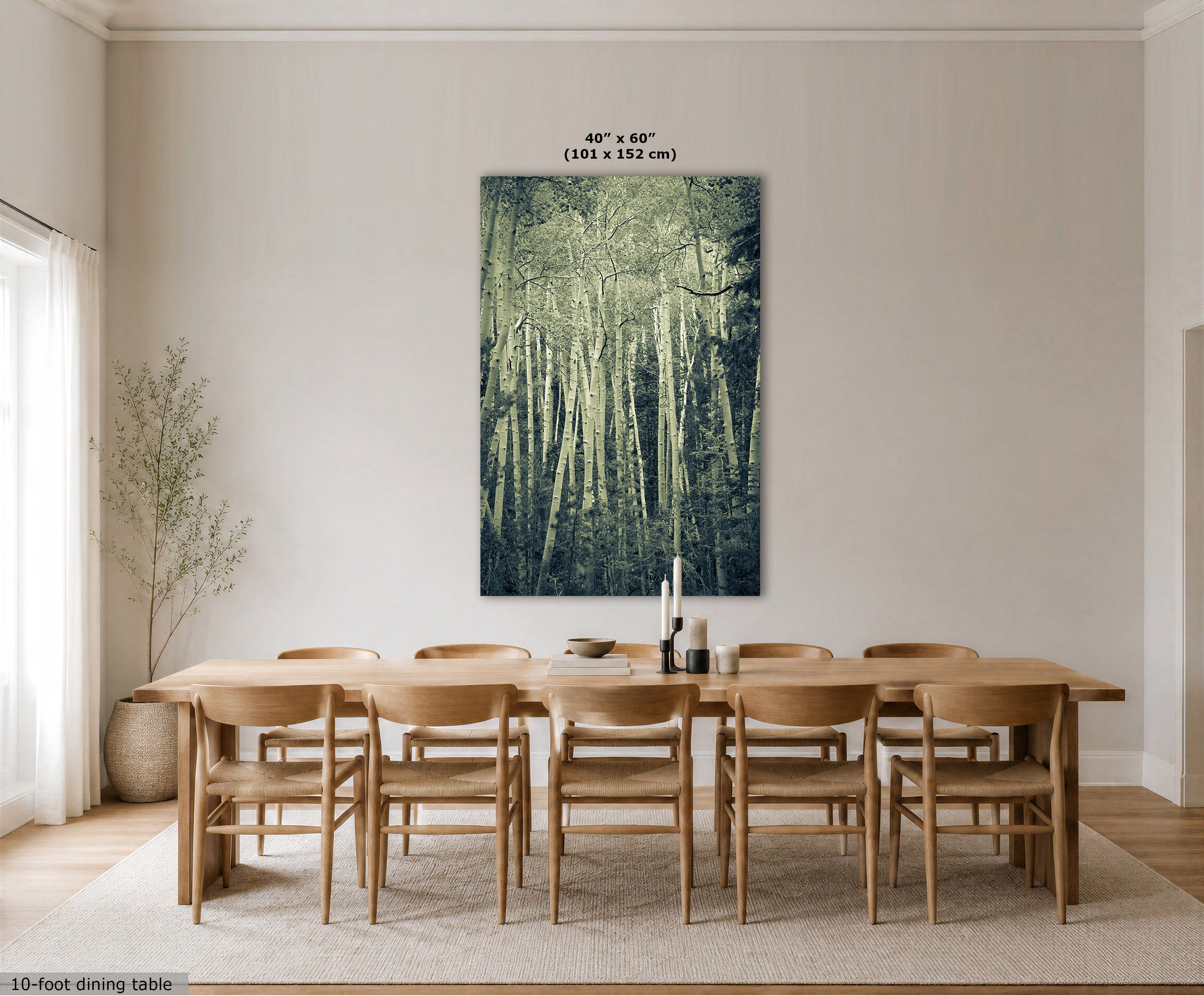 A large vertical canvas print of a forest scene in muted teal and green tones, displayed on a dining room wall above a wooden dining table and chairs. The image includes size text at the top of the canvas and a small label at the bottom left.