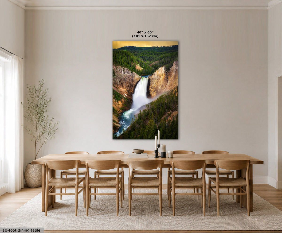 A large vertical wall art print showing a waterfall in a forest canyon, displayed above a wooden dining table and chairs in a bright neutral dining room. The print includes size text above it reading 40 x 60 in (101 x 152 cm).