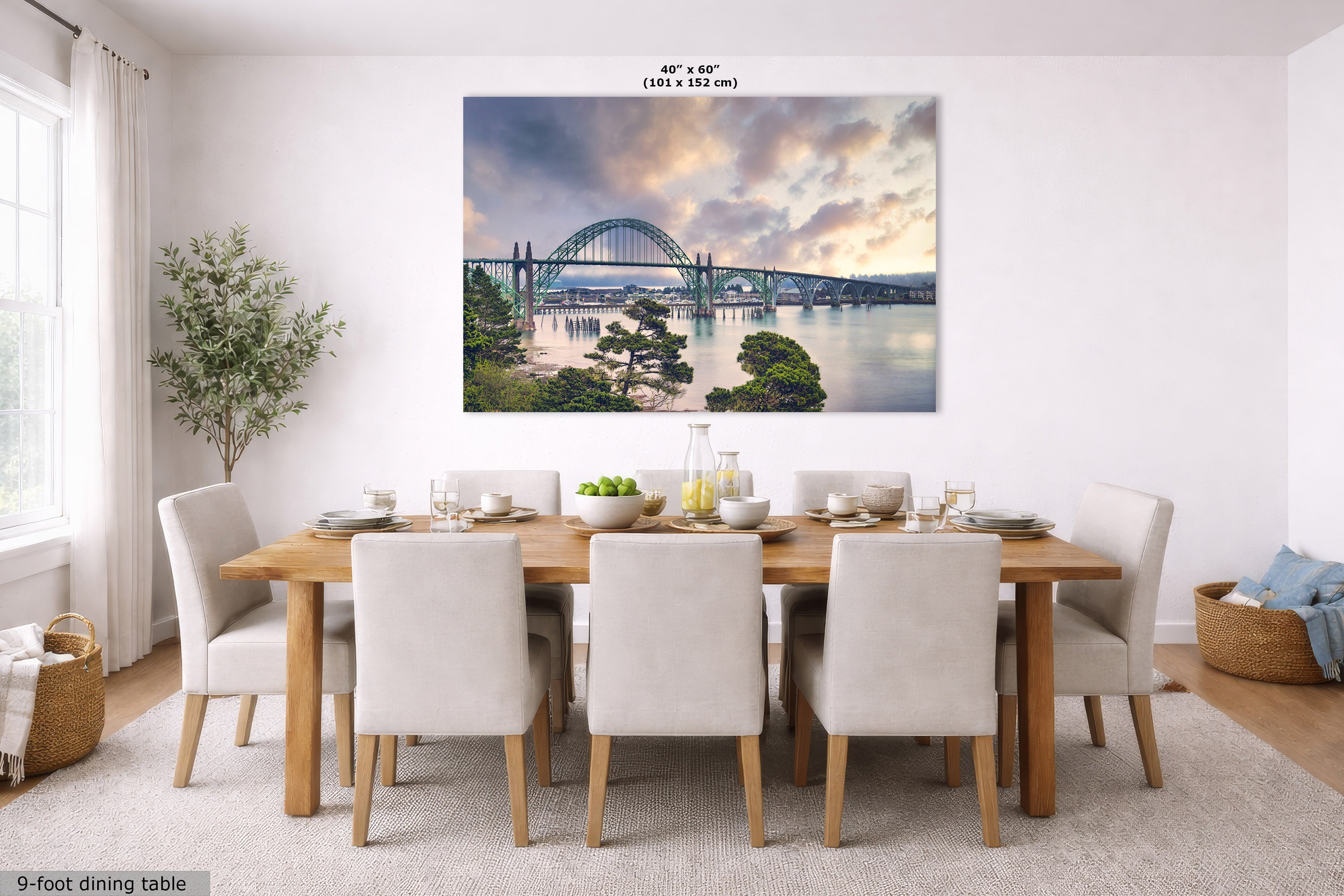 A large rectangular wall art print showing a bridge over water at sunset, displayed above a dining table in a bright modern dining room. The print includes size text reading 40" x 60" (101 x 152 cm).