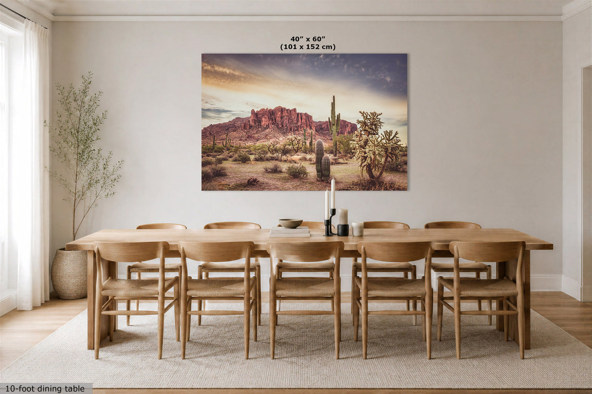 A large rectangular wall art print showing a desert landscape with cacti and red rock mountains, displayed above a wooden dining table and chairs in a bright dining room. The print includes the text '40" x 60" (101 x 152 cm)' at the top.