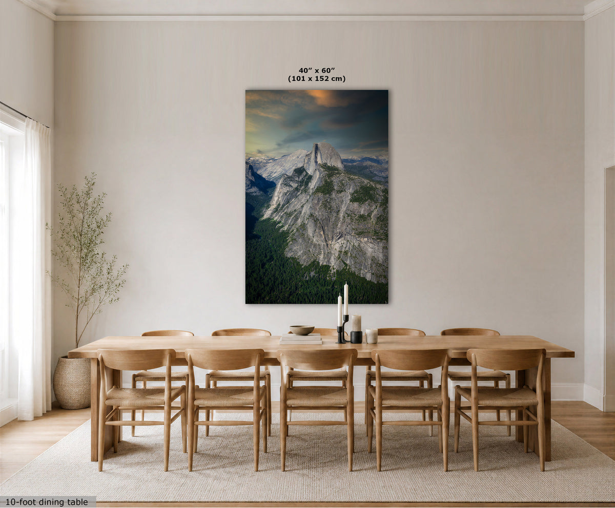 A large vertical wall art print showing a mountain landscape with a glowing sunset, displayed above a wooden dining table and chairs in a bright neutral dining room. Text at the top reads 40 x 60" (101 x 152 cm).