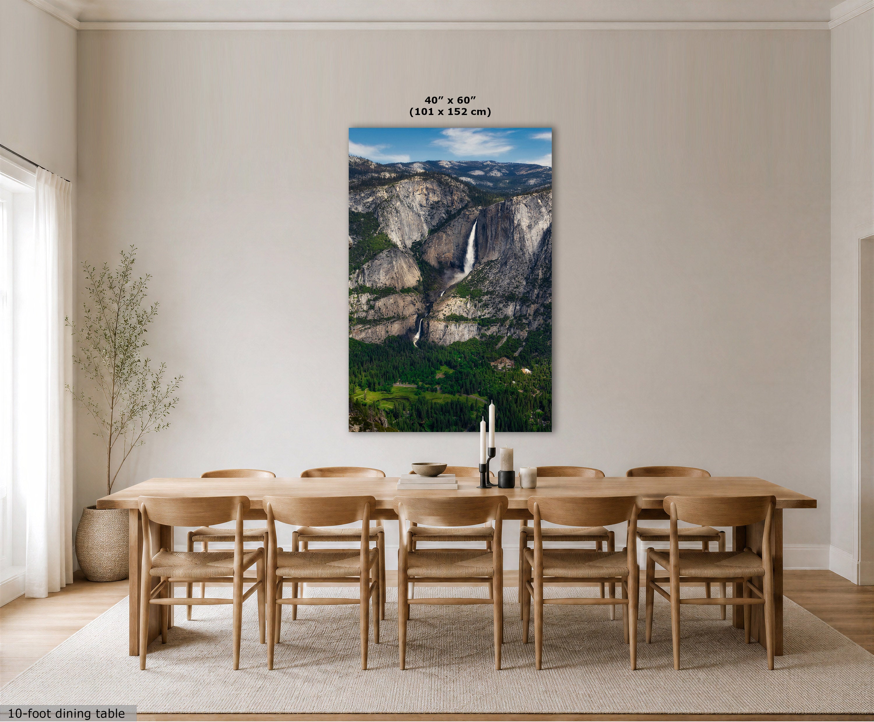 A large vertical canvas print of Yosemite Valley with Yosemite Falls, displayed on a dining room wall above a wooden dining table and chairs. The image includes size text at the top of the print and a small text label in the bottom left corner.