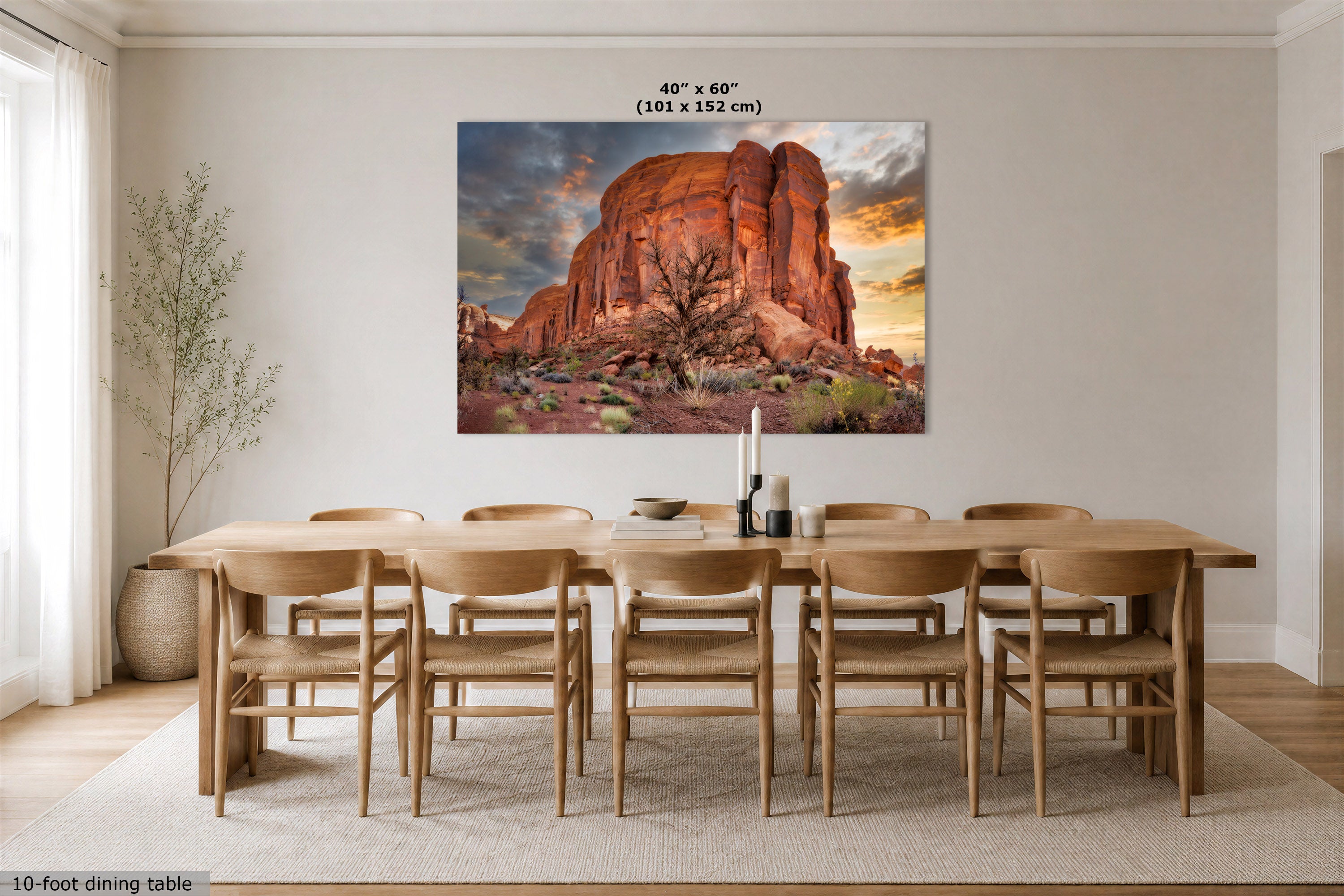 A 40" x 60" canvas print of a red rock desert landscape at sunset, displayed on a dining room wall above a wooden dining table and chairs. The image includes a size label and a 10-foot dining table scale overlay.