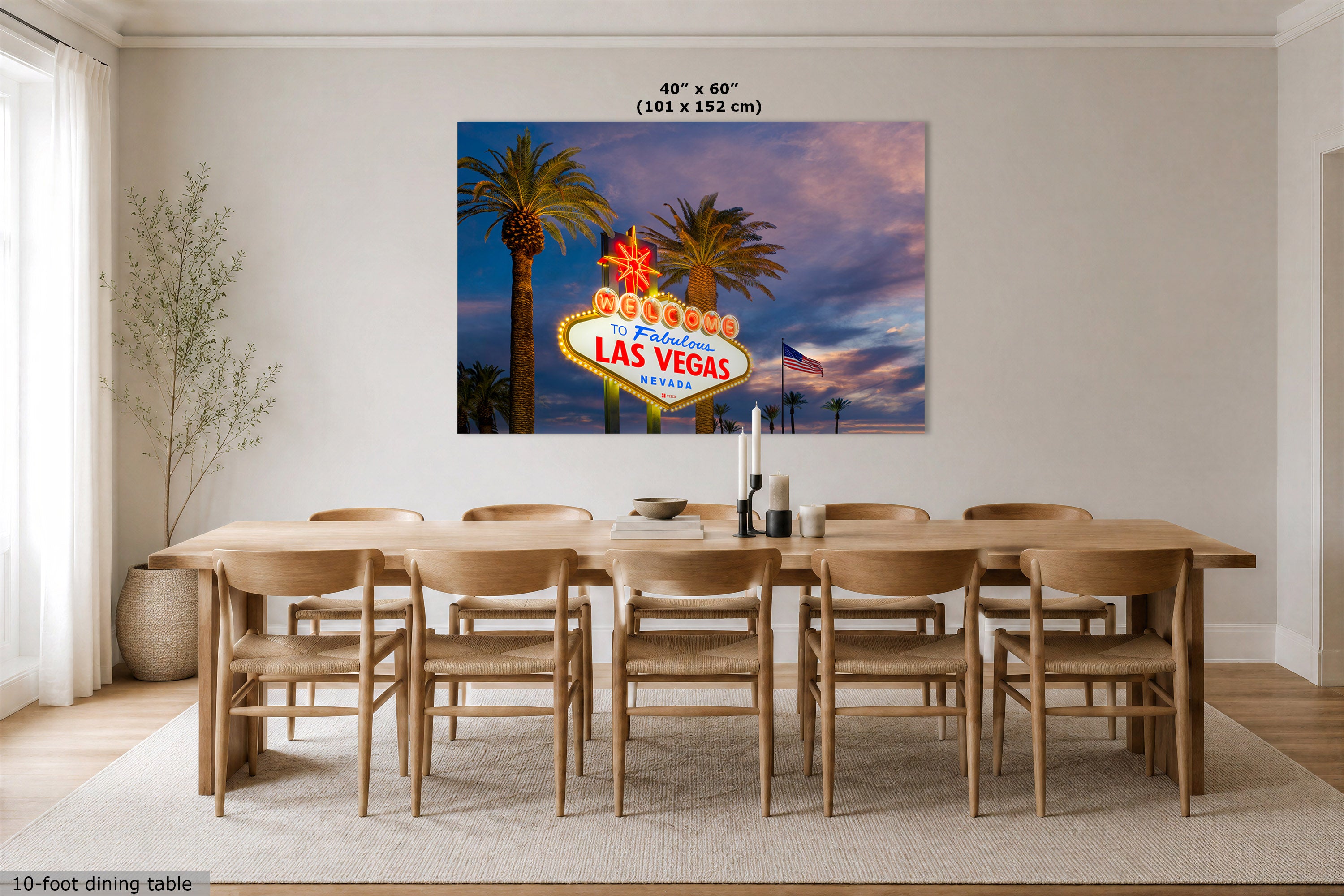 A 40" x 60" canvas print of the Las Vegas skyline, featuring the famous neon sign and palm trees against a sunset sky, displayed on a dining room wall above a wooden dining table and chairs.