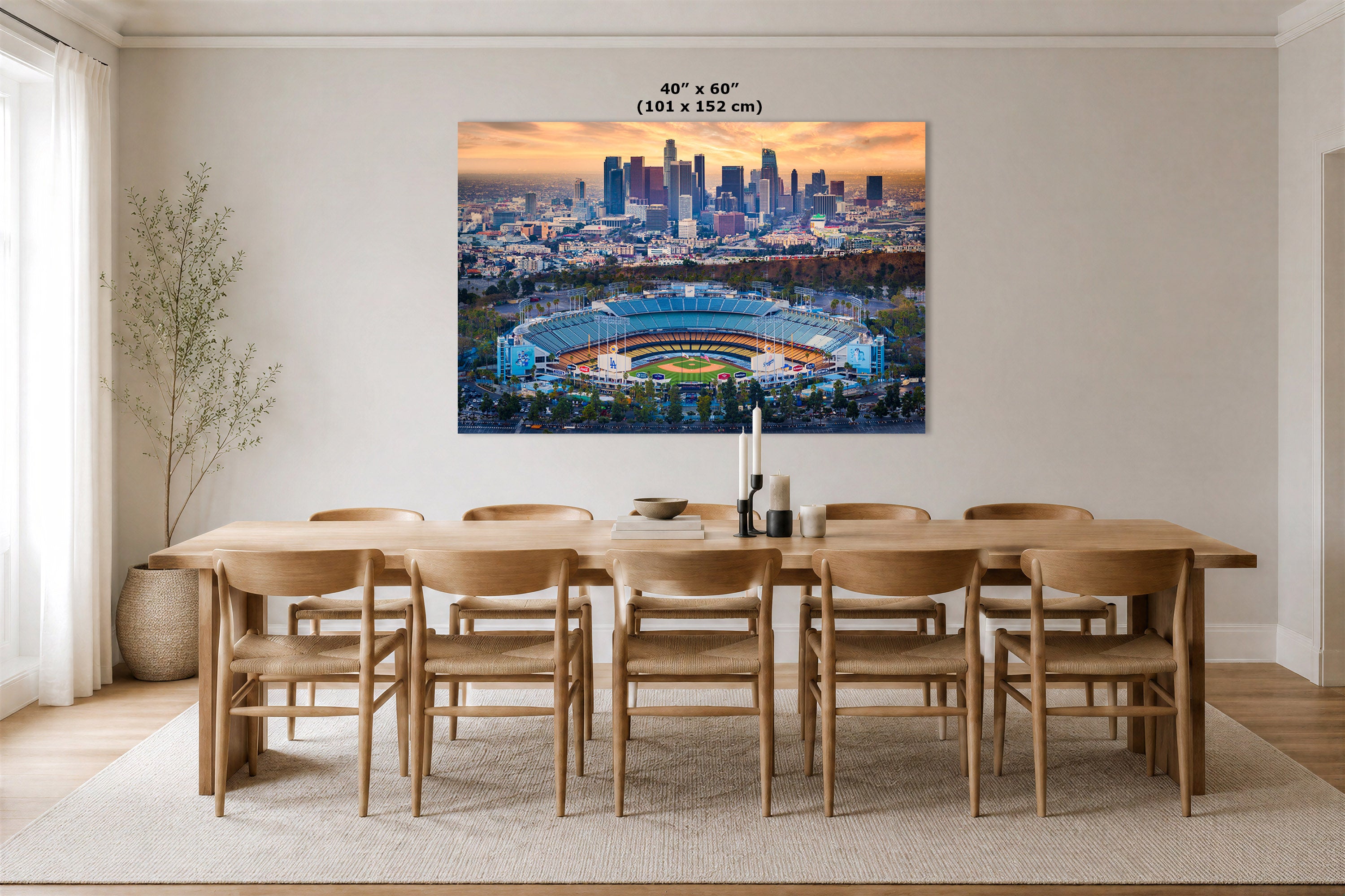 A large Dodger Stadium wall art print showing the stadium and the Los Angeles skyline at sunrise, displayed above a wooden dining table and chairs in a bright, neutral dining room. The print includes the text '40" x 60" (101 x 152 cm)'.