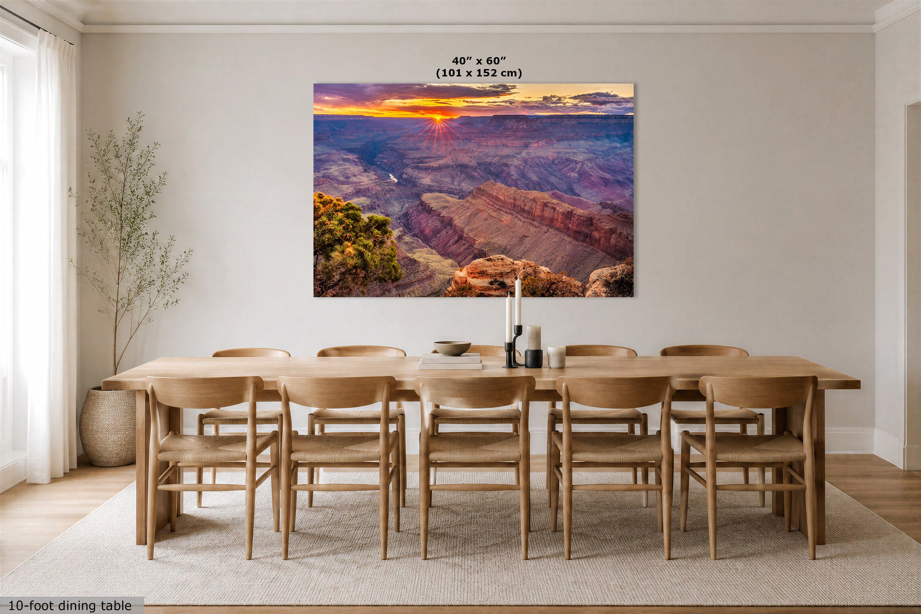 A large rectangular wall art print showing a Grand Canyon sunset hangs above a wooden dining table and chairs in a bright, modern dining room. The print includes size text at the top reading 48 in x 60 in (101 x 152 cm).