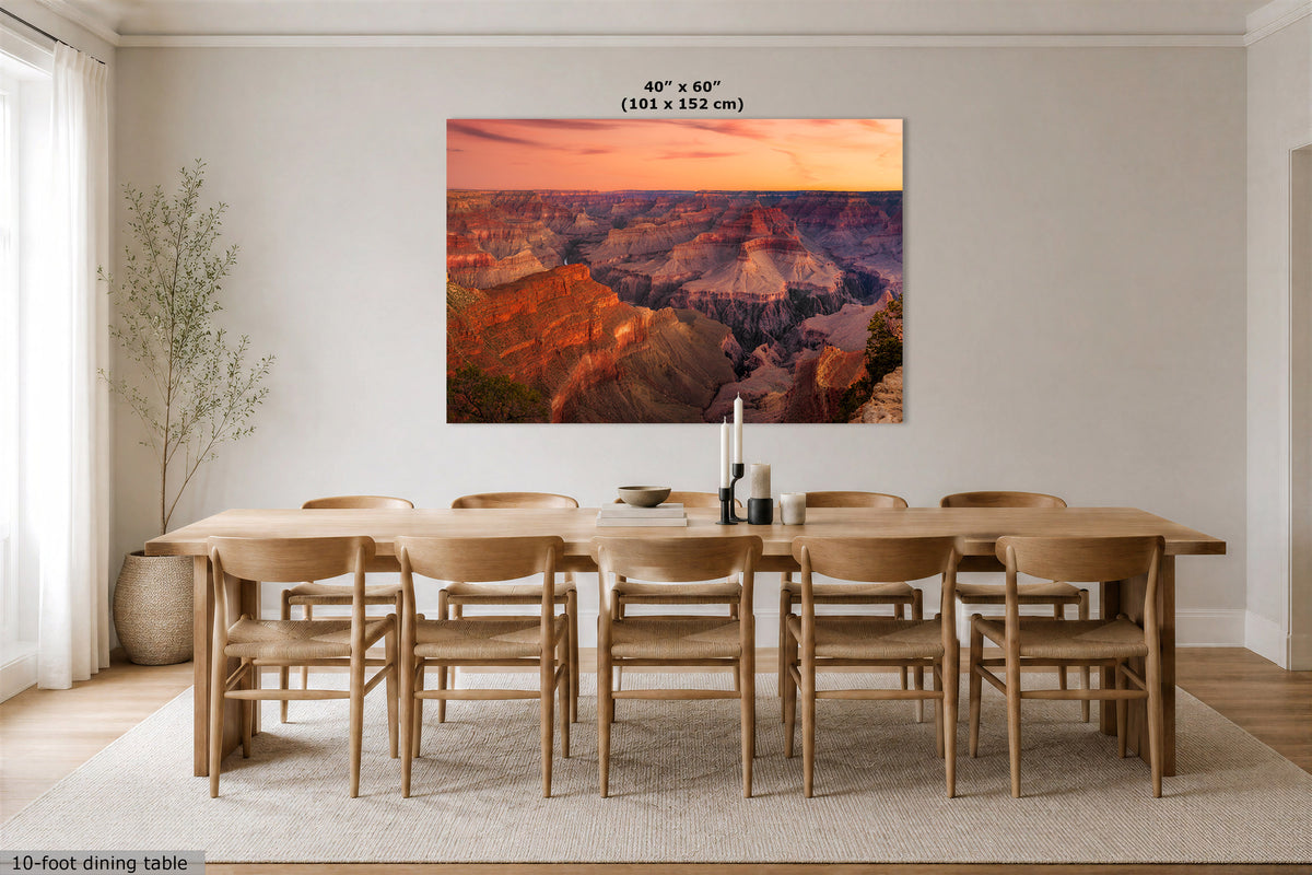 A large rectangular wall art print showing a canyon landscape at sunset hangs above a 10-foot dining table and chairs in a bright, modern dining room. The print includes the text '40" x 60" (101 x 152 cm)' near the top.