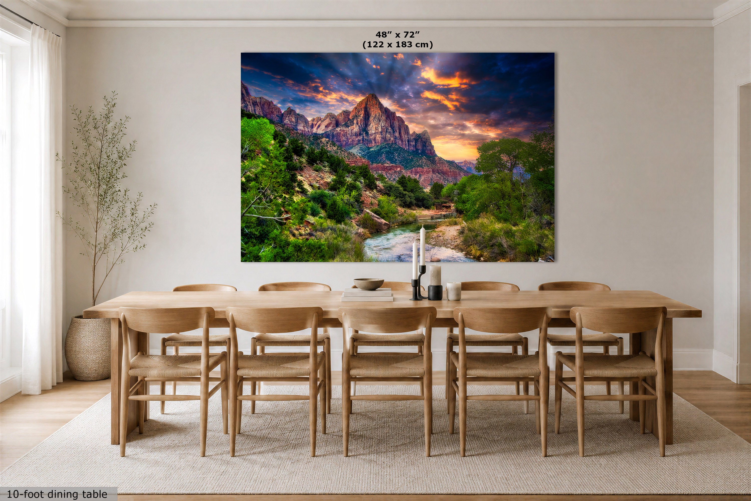 A large wall art print showing a colorful desert canyon landscape at sunset hangs above a wooden dining table and chairs in a bright dining room. The print includes size text at the top reading 48" x 72" (122 x 183 cm).