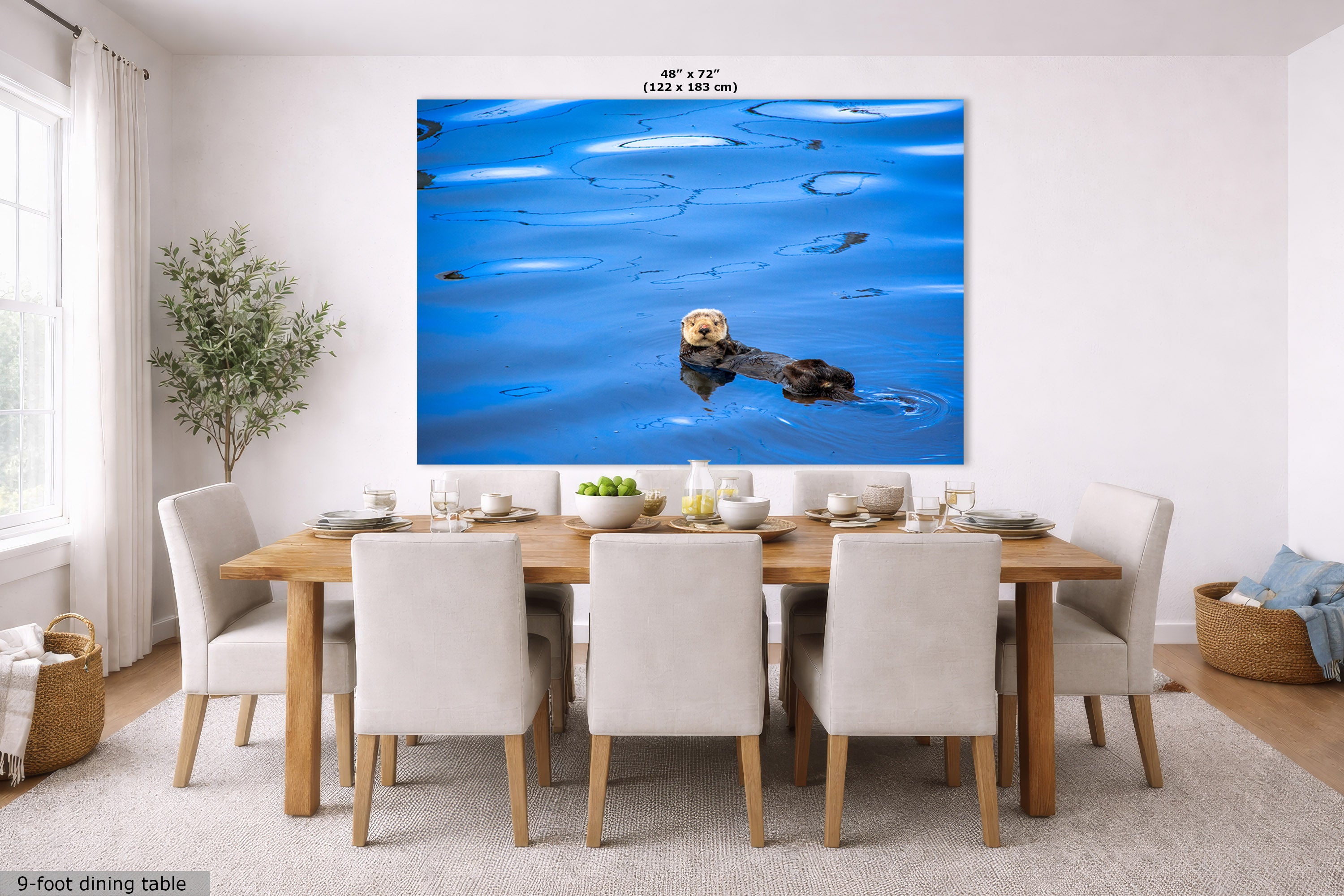 A large wall art print showing a sea otter floating on bright blue water, displayed above a dining table in a modern dining room. The print has dimensions labeled at the top as 48" x 72" (122 x 183 cm).