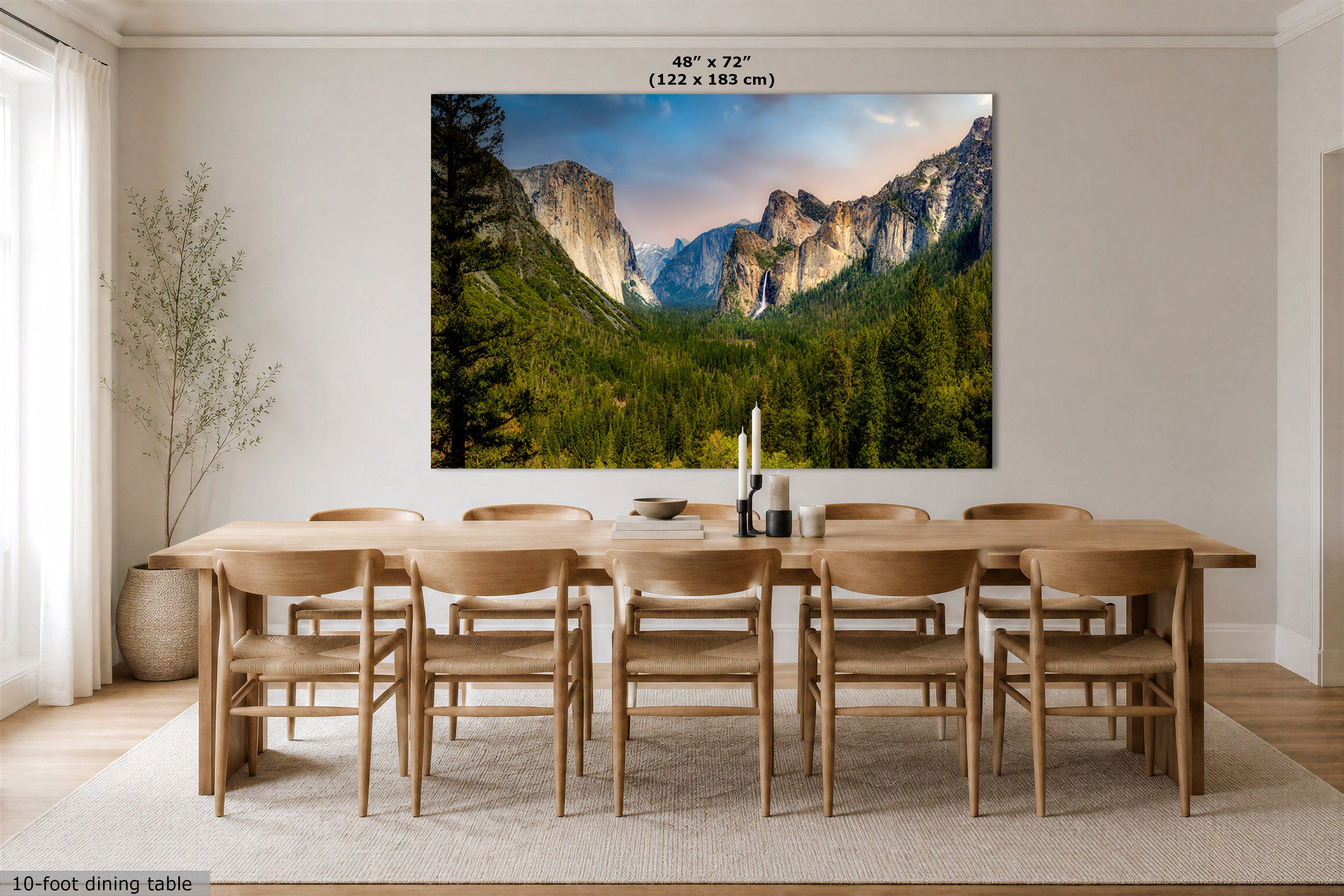 A large wall art print showing a mountain valley landscape with green trees and rocky cliffs, displayed above a wooden dining table and chairs in a bright dining room. Text at the top reads 48" x 72" (122 x 183 cm), and a small note at the bottom left says 10-foot dining table.