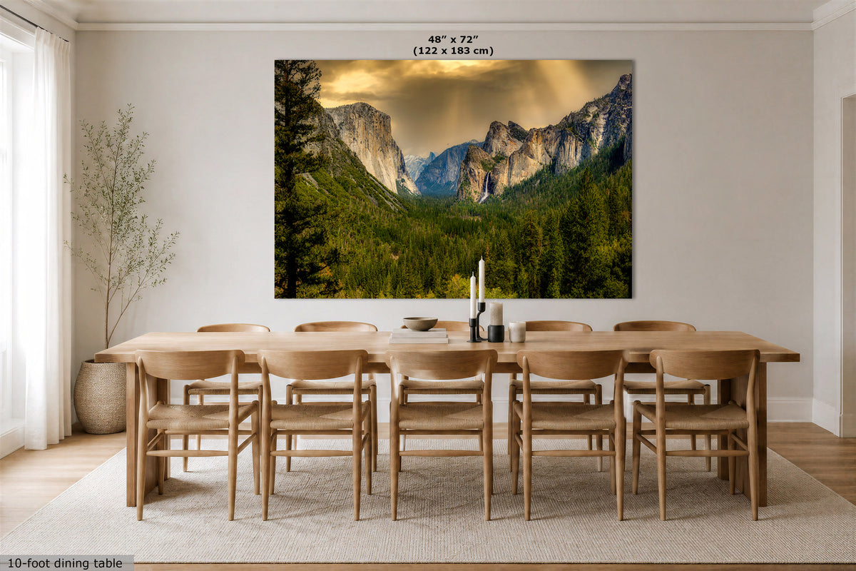 A large wall art print showing a mountain valley landscape with trees and dramatic clouds, displayed above a wooden dining table and chairs in a bright dining room. Text at the top reads 48" x 72" (122 x 183 cm), and a small note at the bottom left says 10-foot dining table.