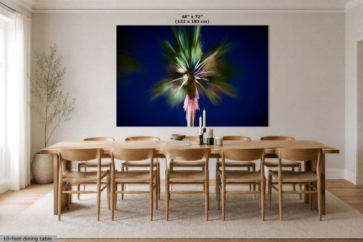 A large wall art print showing an abstract blurred green and pink palm tree against a deep navy blue background, displayed in a modern dining room above a wooden dining table and chairs. The image includes a size label at the top and a 10-foot dining table label at the bottom left.