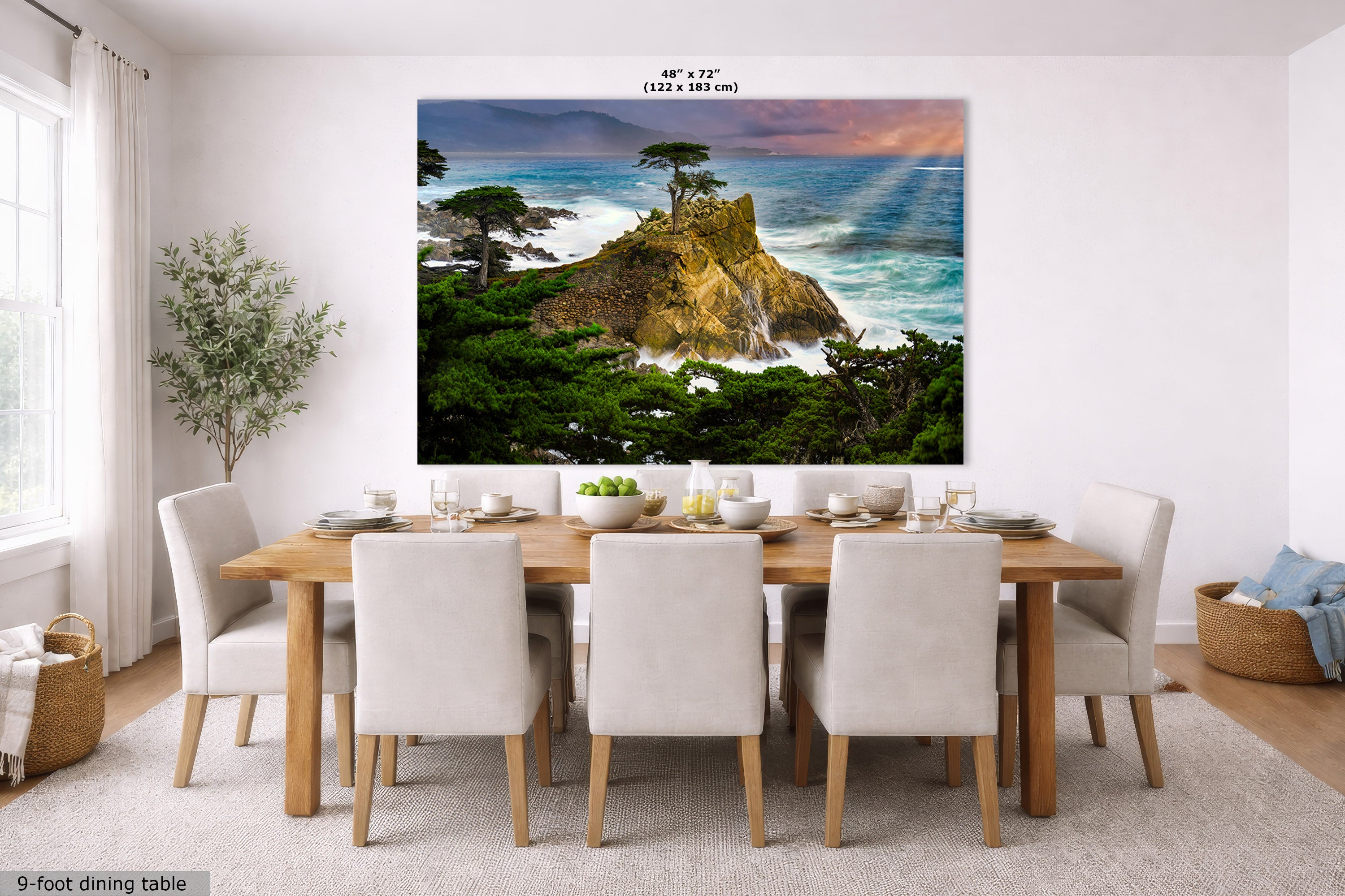 A large wall art print showing the Lone Cypress tree, a rocky coastal cliff with green trees and ocean waves under a colorful sunset sky, displayed above a dining table in a bright modern room. Text at the top reads 48" x 72".