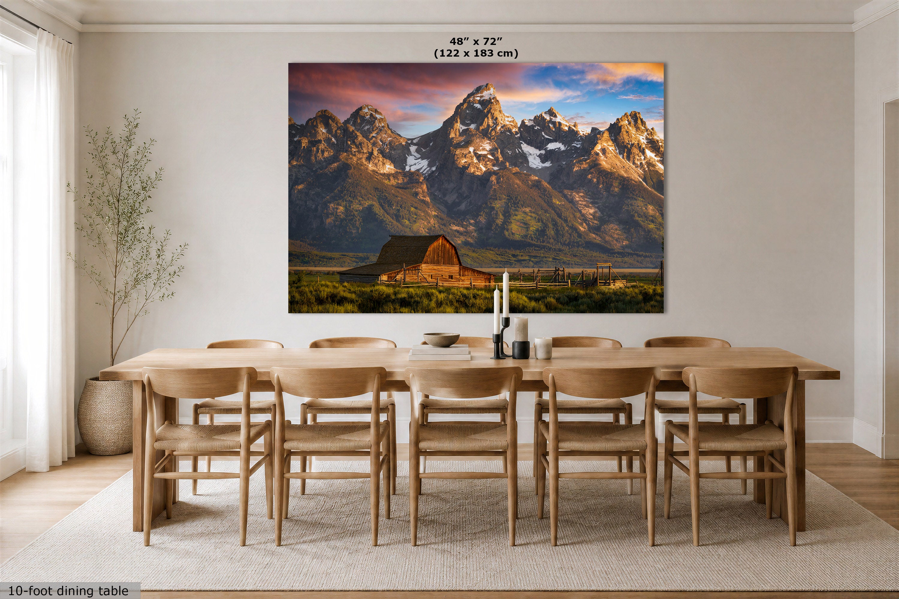 A large wall art print depicting the Grand Teton mountain landscape with a barn and sunset sky, displayed above a wooden dining table in a bright dining room. Text at the top reads 48" x 72" (122 x 183 cm), and text at the bottom left says 10-foot dining table.