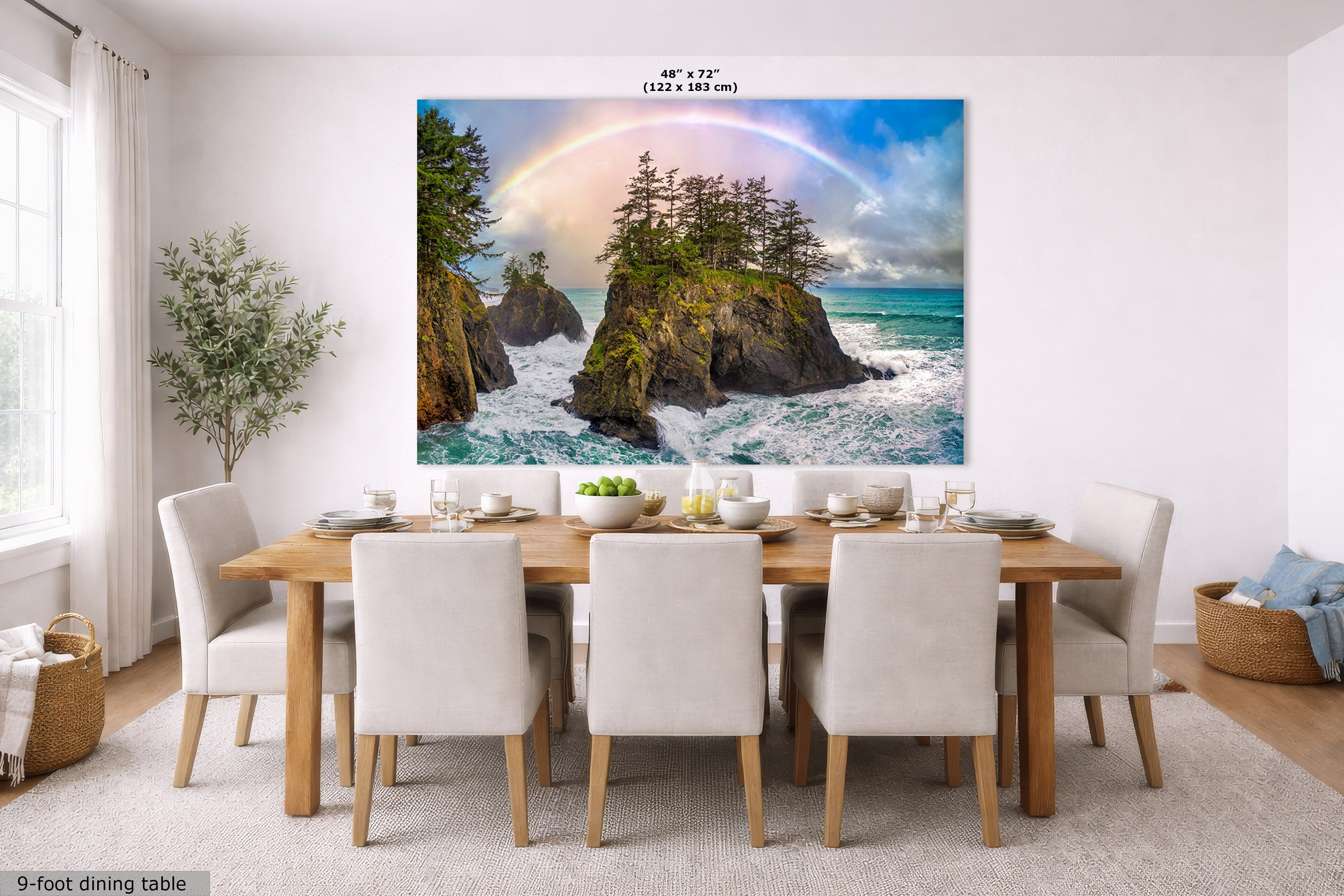 A large wall mural or canvas print depicting a dramatic coastal scene with rocky cliffs, ocean waves, and a rainbow, displayed above a dining table in a bright modern room. Text at the top reads 48" x 72" and at the bottom left says 9-foot dining table.