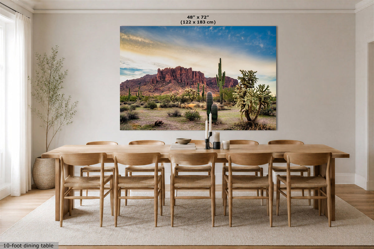 A large rectangular wall art print showing a desert landscape with red rock formations, cacti, and a blue sky, displayed above a wooden dining table in a bright dining room. Text at the top reads 48" x 72" (122 x 183 cm).