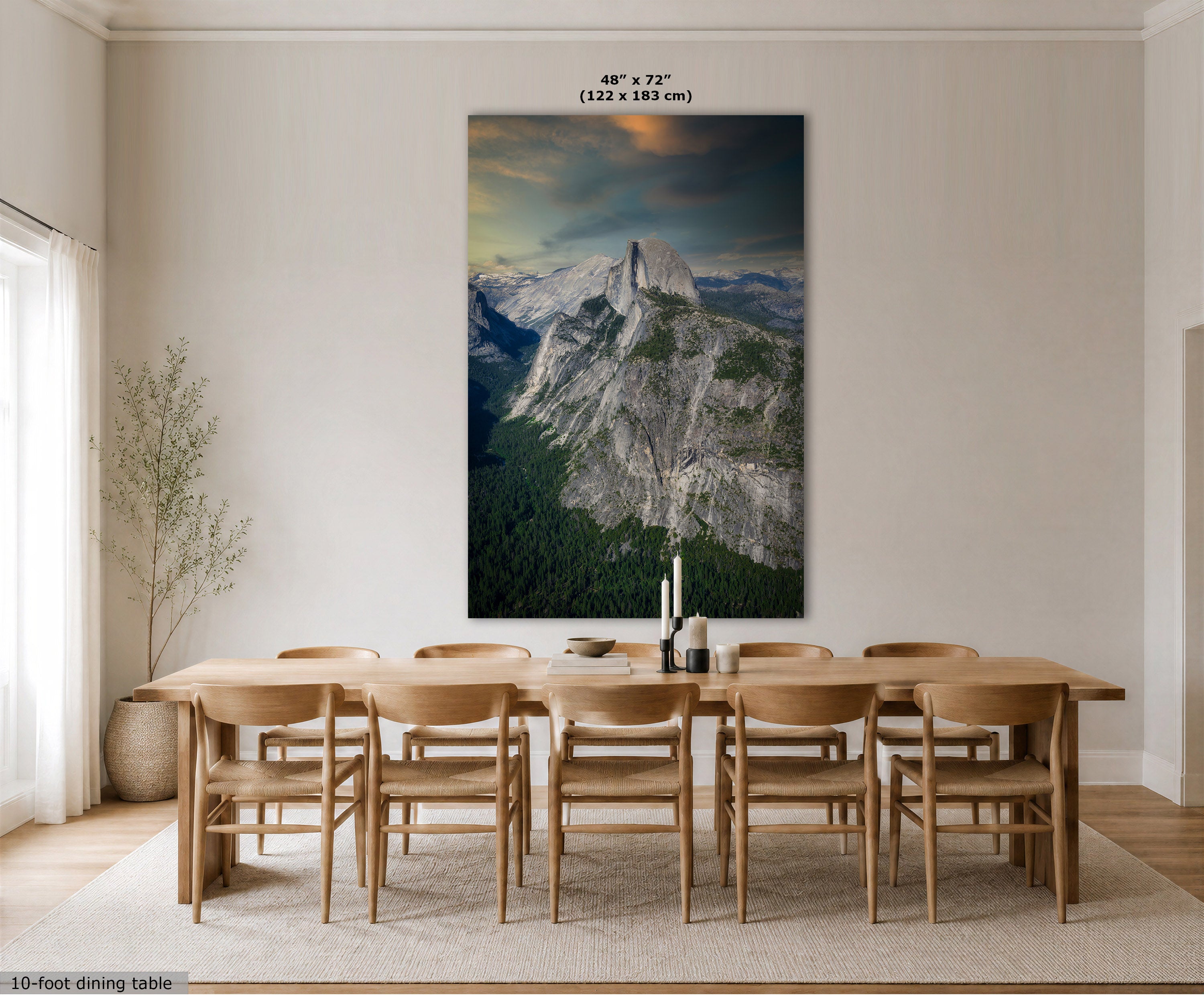 A large vertical wall art print showing a mountain landscape hangs above a wooden dining table and chairs in a bright, modern dining room. The print includes a size label at the top reading 48" x 72" (122 x 183 cm).