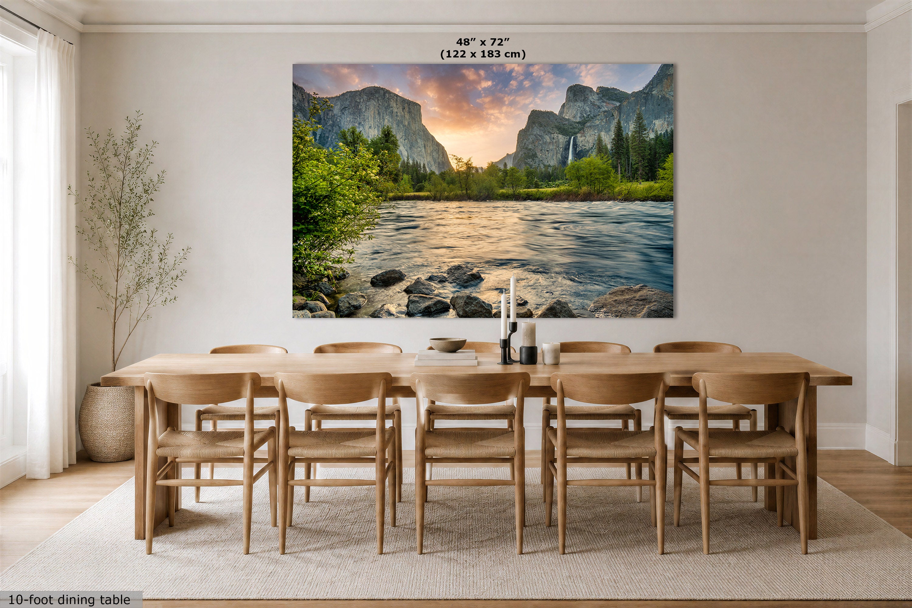 A large wall art print depicting a scenic mountain river landscape with sunset light, hung above a wooden dining table and chairs in a bright modern dining room. Text at the top of the print shows dimensions 48" x 72" (122 x 183 cm).