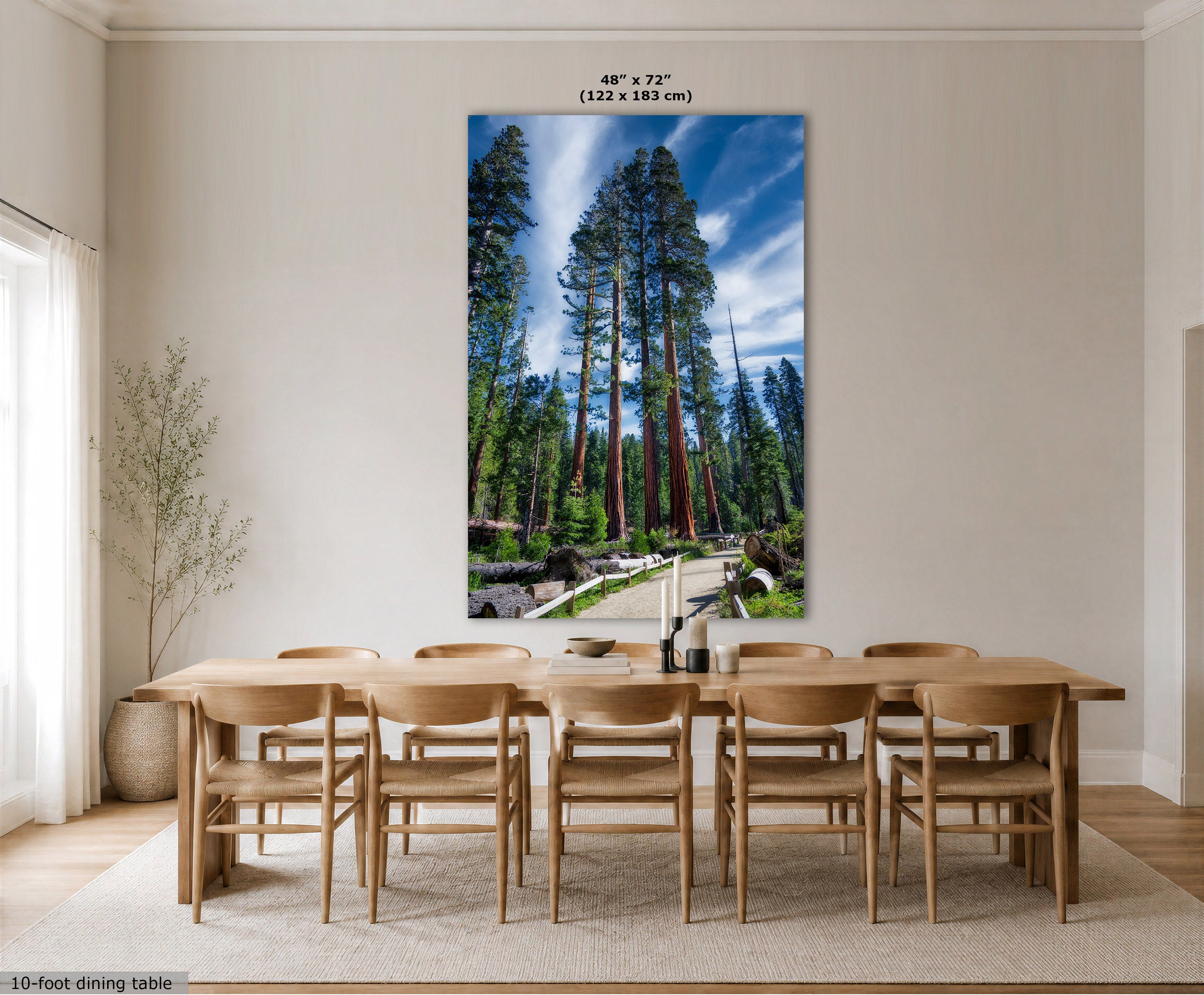 A large vertical wall art print showing a forest scene with tall trees and a blue sky, displayed above a wooden dining table and chairs in a bright dining room. The print includes size text at the top reading 48" x 72" (122 x 183 cm).