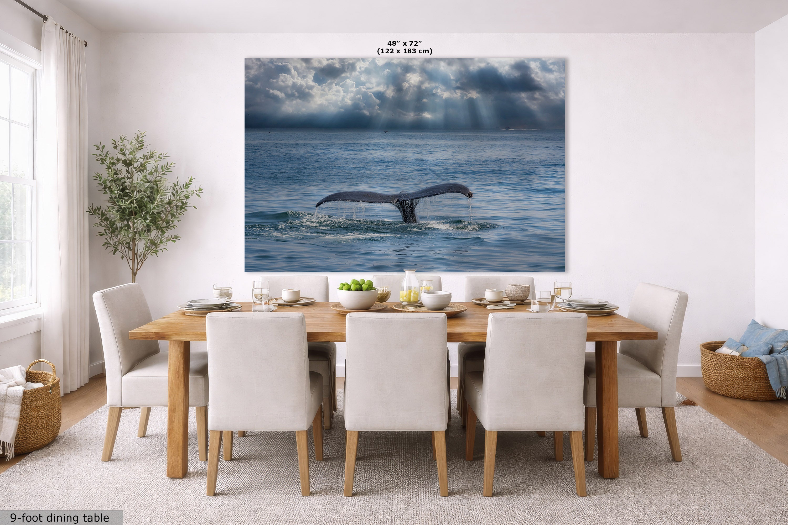 A large wall art print showing a whale tail diving in a stormy blue ocean, displayed above a dining table in a bright modern room. The print includes size text at the top and a small label at bottom left reading 9-foot dining table.